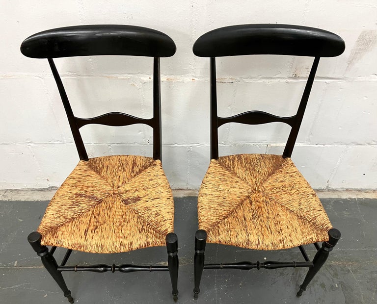Pair light and elegant c. 1940s Chiavari dining chairs. The original design dates to the early 19th c., by Giuseppe Gaetano Descalzi. Painted wood with original rush seats. This version was the model Gio Ponti interpreted into his famous