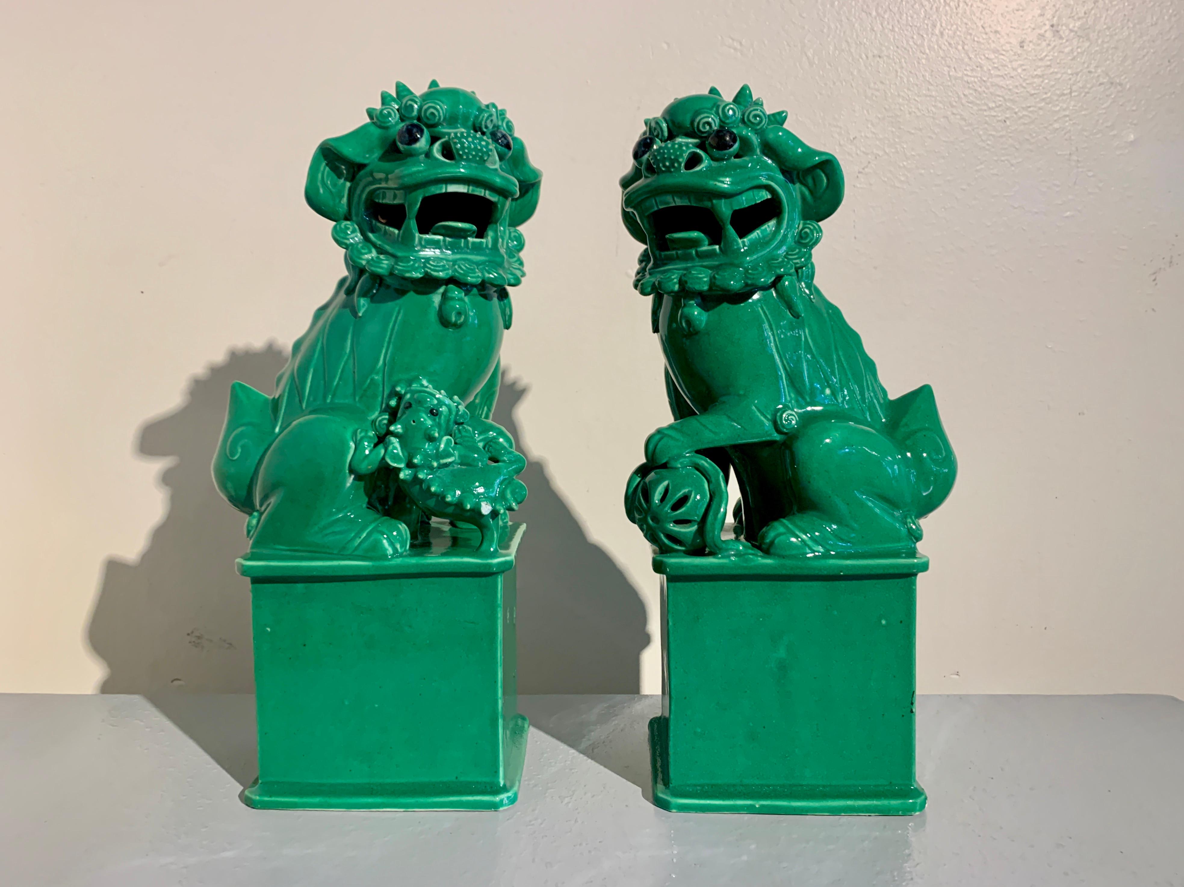 A darling and charming pair of vintage Chinese green glazed porcelain foo dogs or foo lions, late 20th century, circa 1970's, China.

The delightful pair of foo dogs, also referred to as foo lions, are raised upon tall rectangular pedestals. The foo