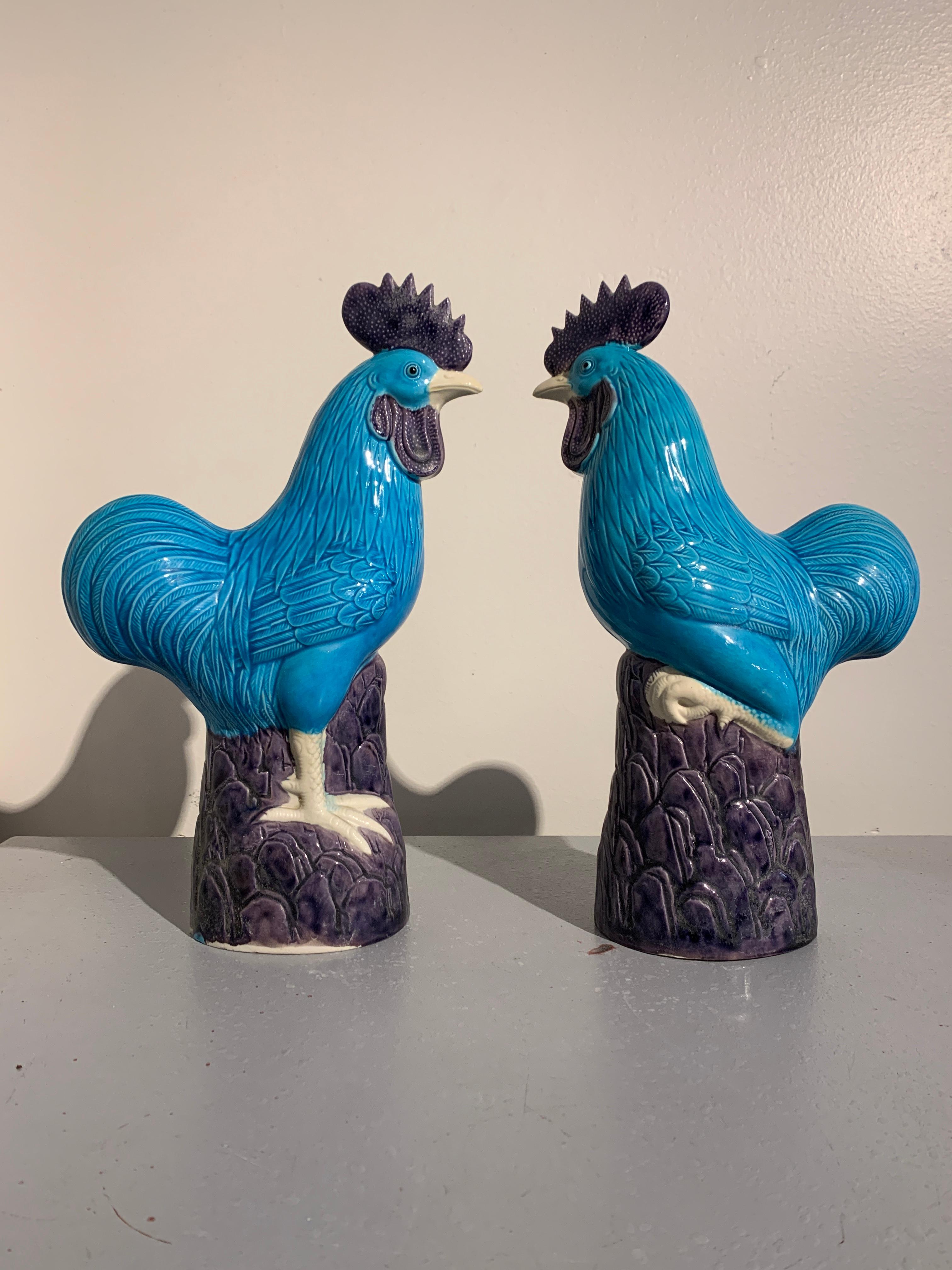 A charming pair of porcelain Chinese export models of roosters, late 20th century.

The roosters modeled standing upon rocky perches, with one leg raised. Their large tails swooping gracefully behind them, their crests standing tall upon their