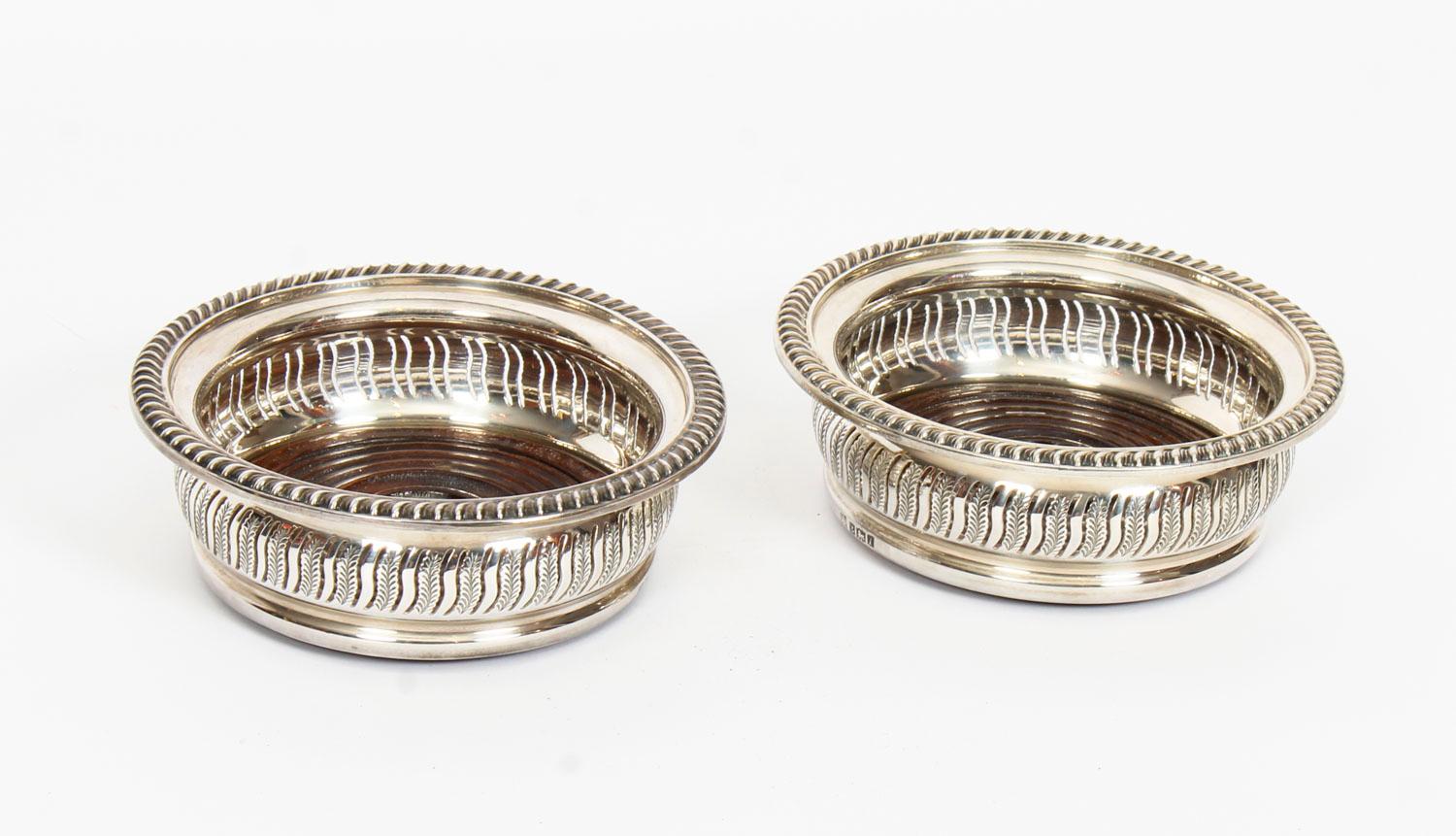 A superb pair of mid-20th century sterling silver wine coasters, by the Barker Ellis Silver Co, Birmingham, 1968.

Of circular form with pierced fern decoration, gadroon borders and turned wooden bases with plain buttons.
Provenance:

James
