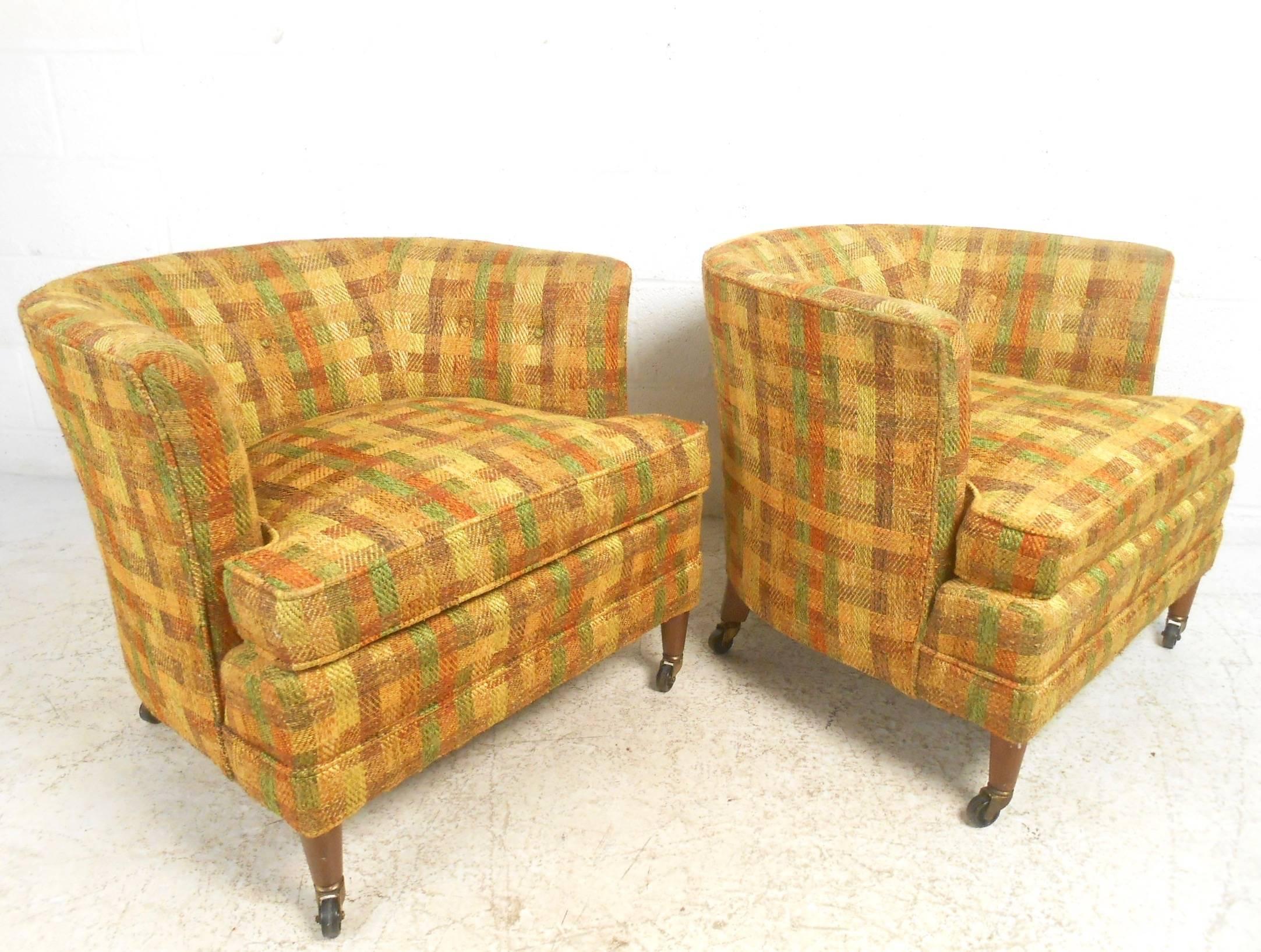 This stylish pair of retro modern club chairs features vintage plaid upholstery, barrel back seats, and walnut legs with casters for easy arrangement. This impressive mix of style and comfort makes this the perfect pair of Mid-Century Modern lounge