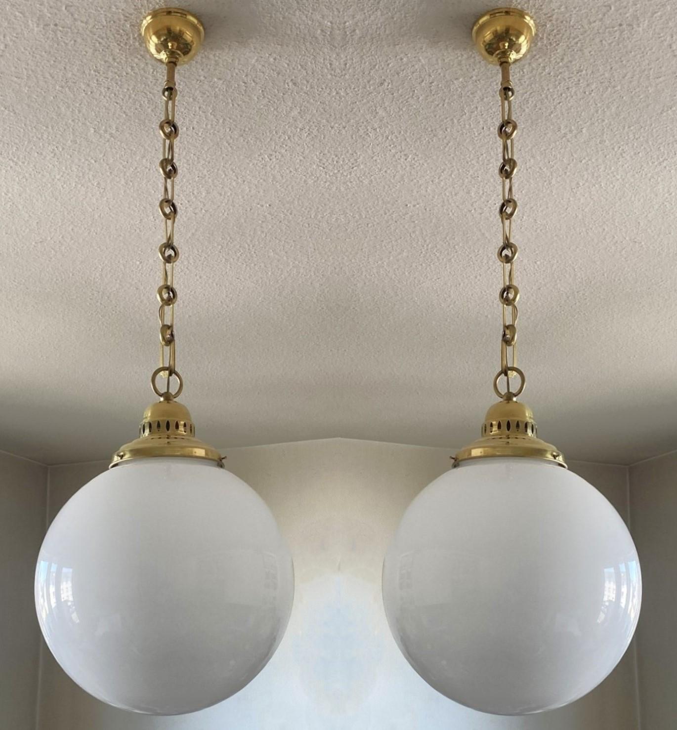Ein Paar Landhaus-Pendelleuchten aus mundgeblasenem Opalglas mit Messinggalerie, Frankreich um 1950.
Große Opalglas-Kugel mit Schirmhalterung aus Messing mit durchbrochenen Details für die Lichtprojektion, schöne Messingkette und Baldachin. Mit