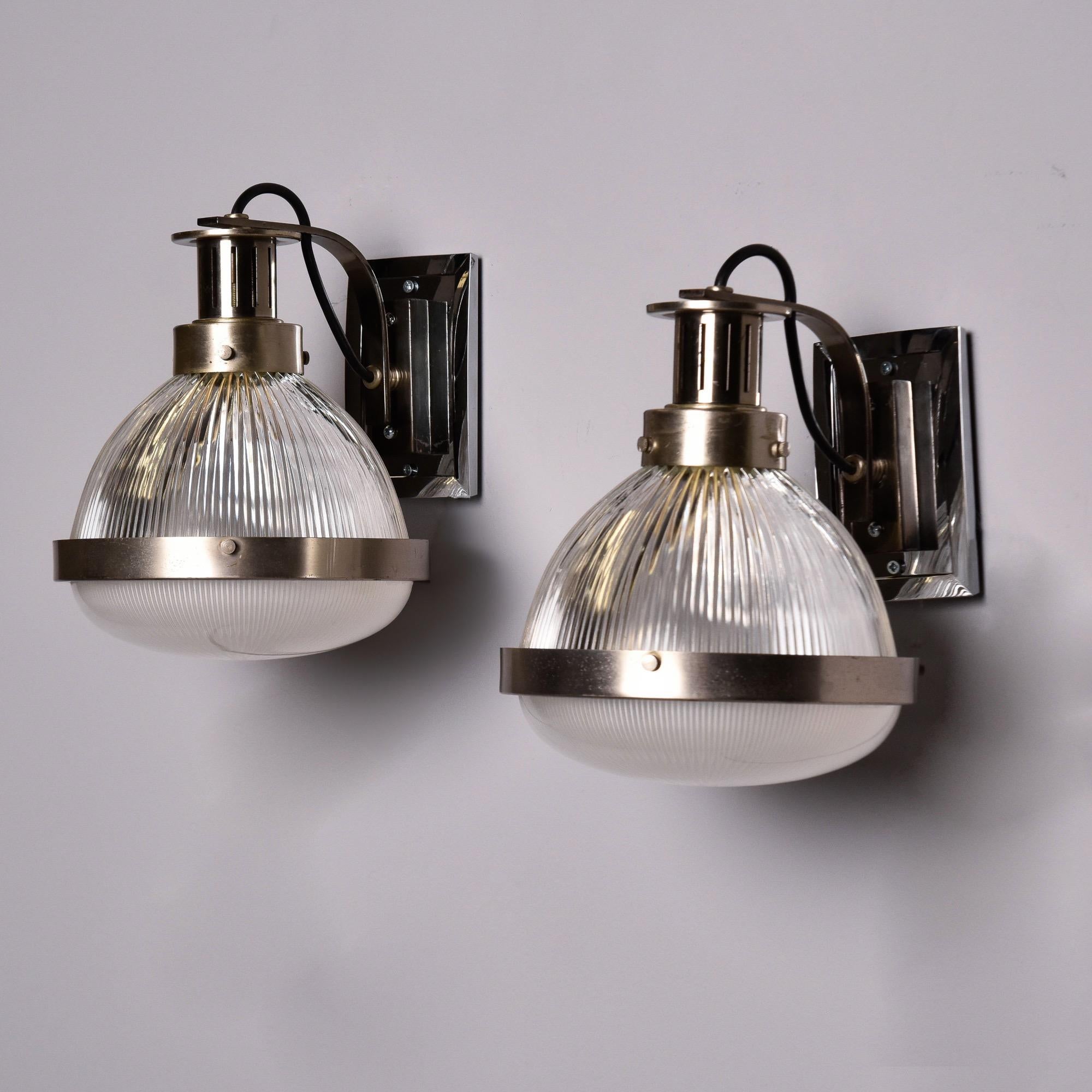 Found in England, this pair of wall lights or sconces date from the 1970s and feature chrome back plates and fittings with globes in clear, ribbed glass toward the top and more opaque glass covers. Each sconce has a single internal standard size