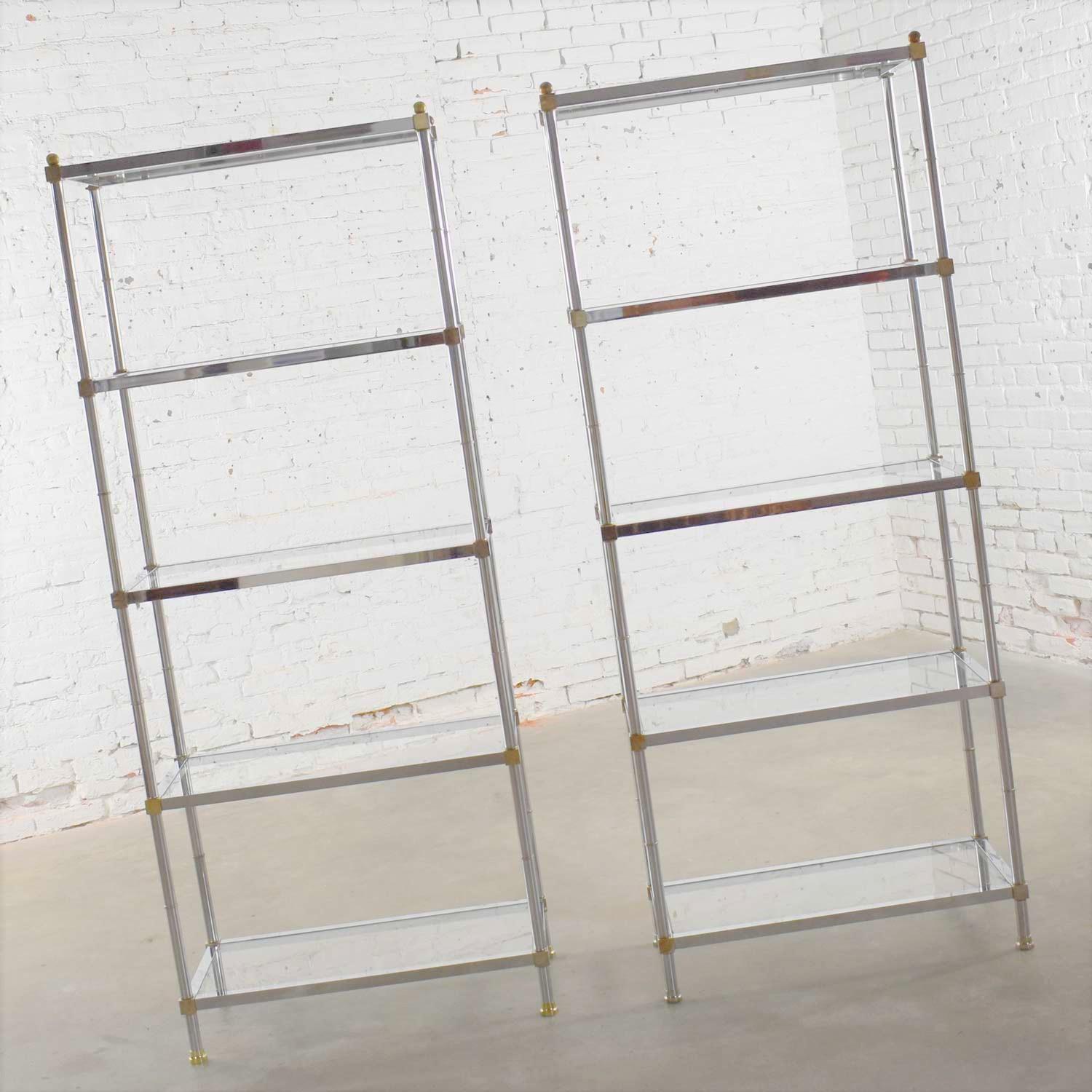 Handsome pair of vintage chrome, brass, and glass étagère display shelves done in the manner of Maison Jansen. They are both in great vintage condition. They do have scratches and marks as you would expect with age and use. We call that patina.