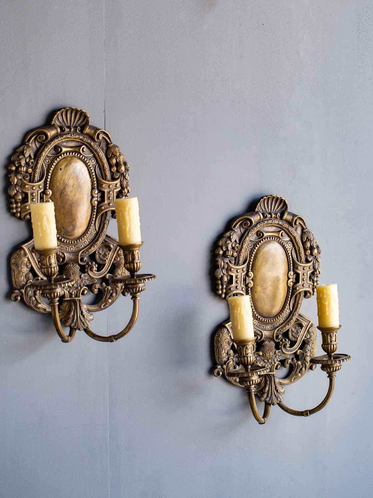 This pair of exceptionally grand scale vintage French Renaissance Louis XIV style bronze sconces, circa 1920 have been freshly wired for American electricity and fitted with wax candle sleeves for the bulbs. Oval in shape with a generous amount of