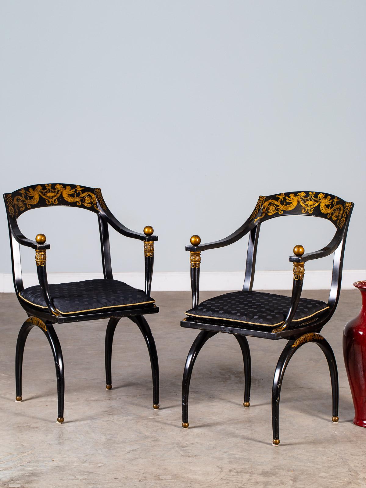 Pair of vintage French Empire ebonized black lacquer gilt wood chairs circa 1950 after Chapuis. These black lacquered chairs have the original hand applied gilt stenciling and decoration reflecting the early nineteenth century facination with the