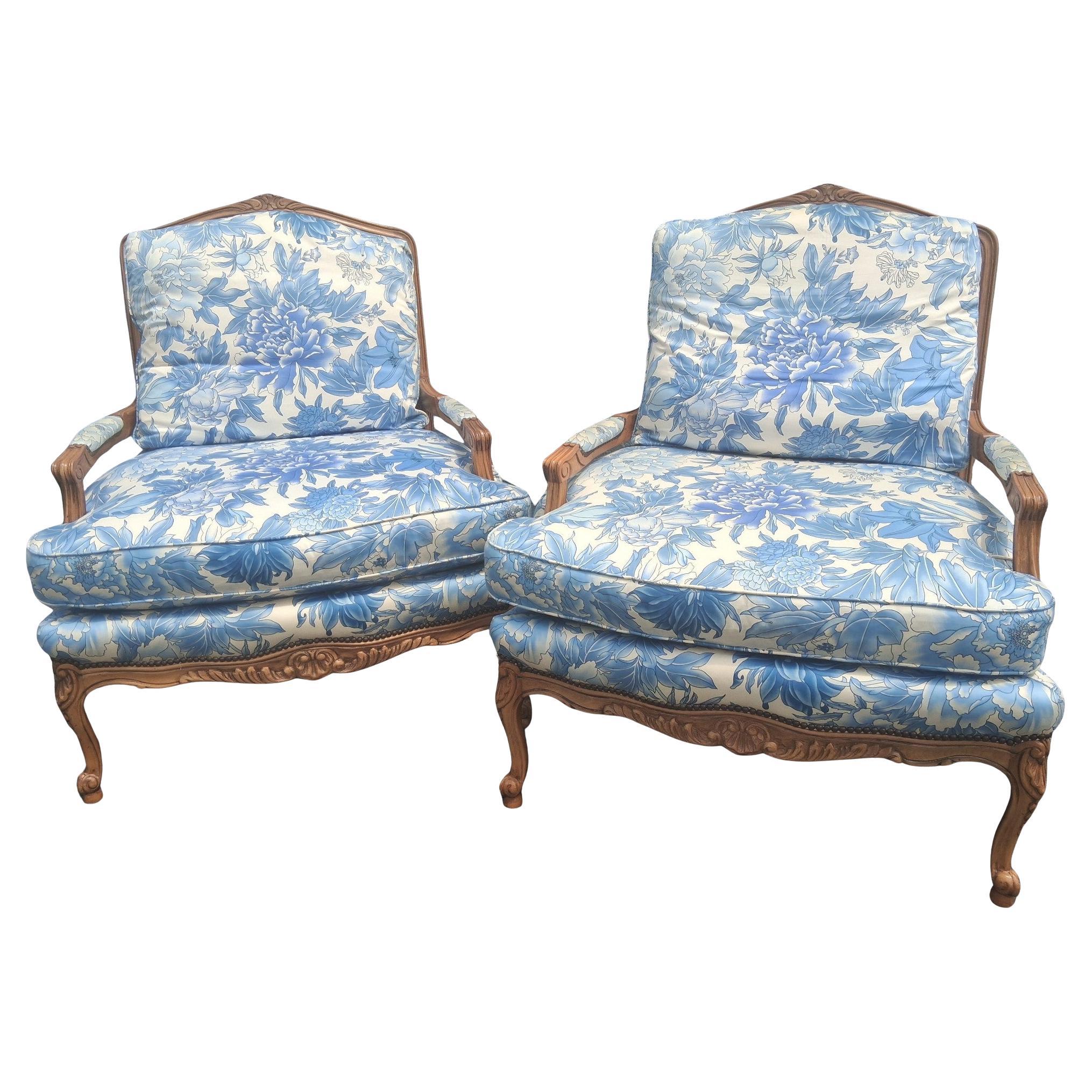 Paar Vintage Französisch Stil Louis XV geschnitzt Nussbaum Floral gepolstert Bergere Stühle von Baker Furniture Company. Sehr hochwertige Designerstühle. Blaue geblümte Polsterung und Stühle sind in sehr gutem Zustand mit minimalen Gebrauchsspuren.