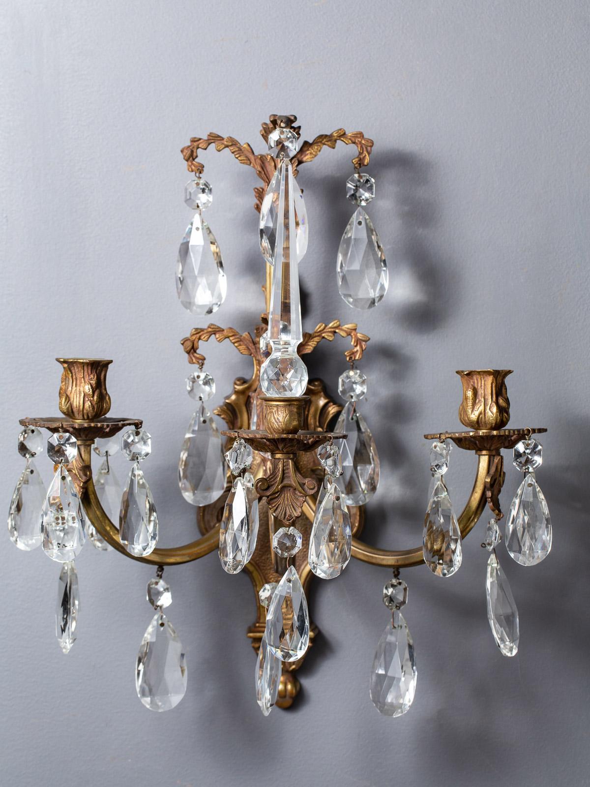 A pair of elegant three-arm vintage French brass and crystal sconces, circa 1940. These sconces have an important component referring the tall cut crystal spikes known as a 
