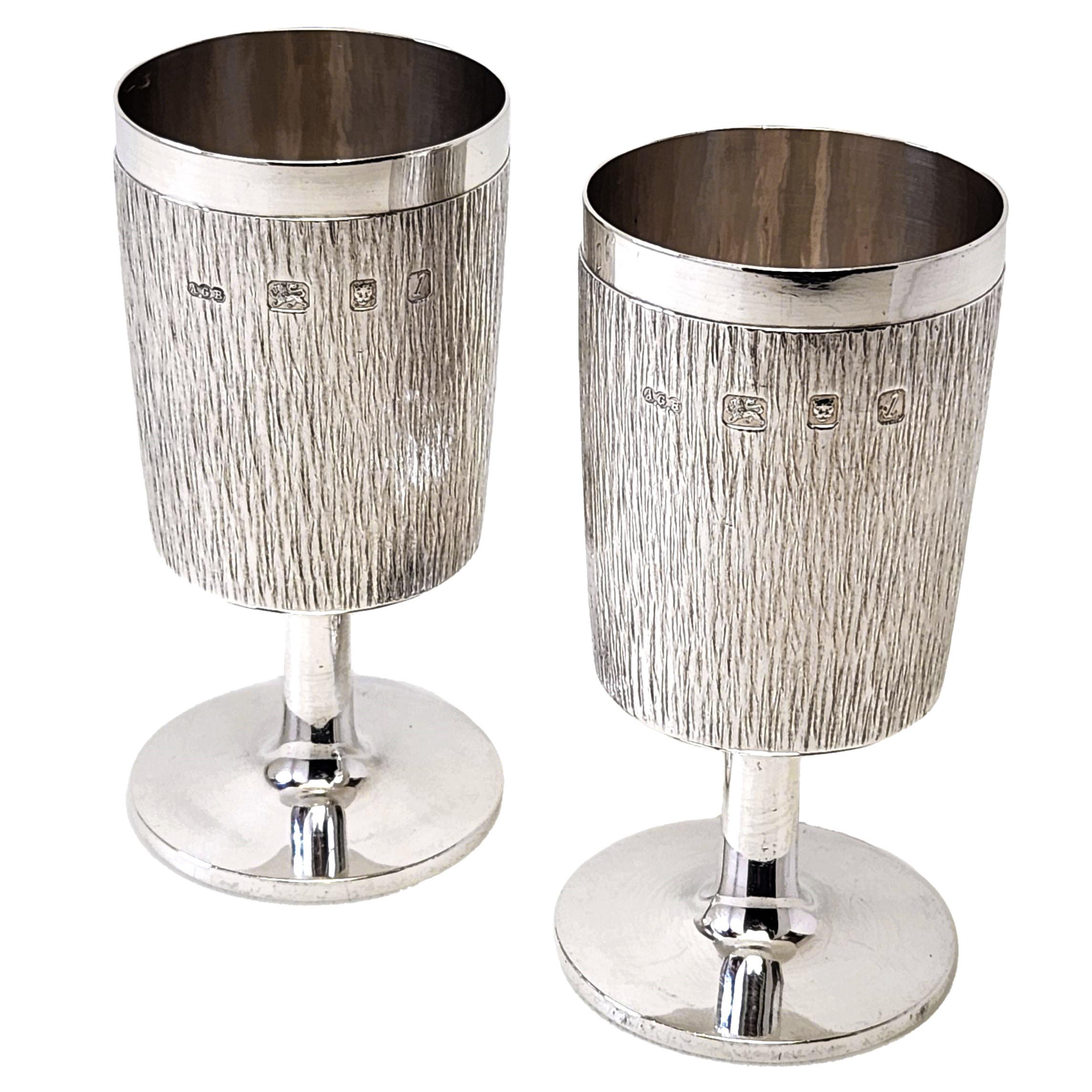 A pair of vintage Solid Silver Goblets embellished with the iconic Bark Patterning that exemplifies Benney's work. The Goblets have a straight sided form and a highly polished spread foot. This pair of Goblets is presented in a fitted blue box with