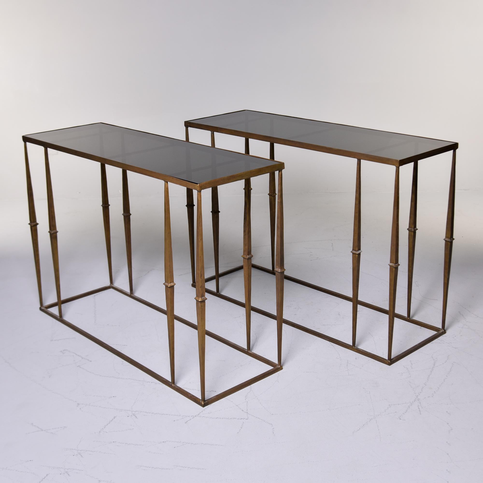Dieses Konsolenpaar wurde in den USA gefunden und stammt aus dem Jahr 2000. Die vergoldeten Eisenfüße sind mit gepaarten Beinen auf einem stabilen Sockel verbunden. Schwarze Glaseinsatz-Tischplatten sind neu und in ausgezeichnetem, neuem Zustand.