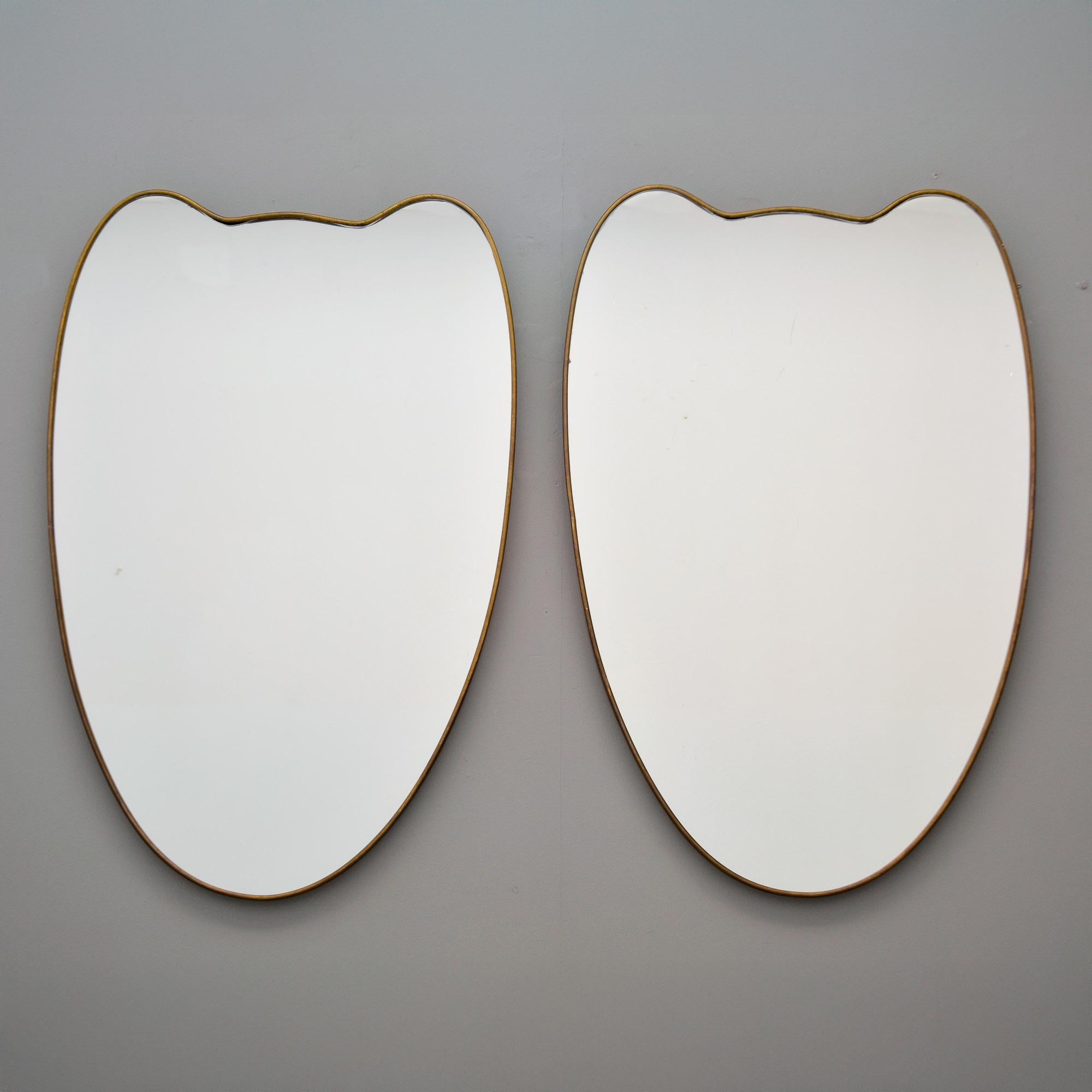 Trovata in Italia, questa coppia di specchi con cornici sottili in ottone risale alla fine degli anni Cinquanta/inizio anni Sessanta. Gli specchi a forma di scudo hanno lo schienale in Wood e cornici in ottone sottili e minimaliste nello stile di