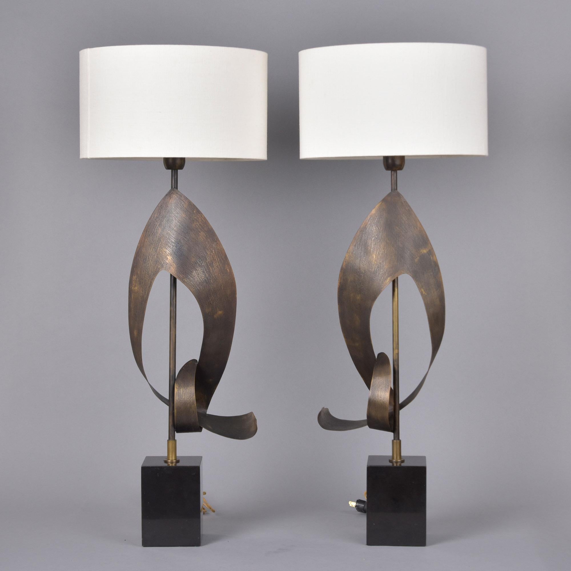 Found in Italy, this pair of brutalist-style table lamps date from the 1970s. Base is black marble or granite with metal center shafts that support abstract, sculptural metal elements. White fabric shades found with lamps. Sockets are standard size