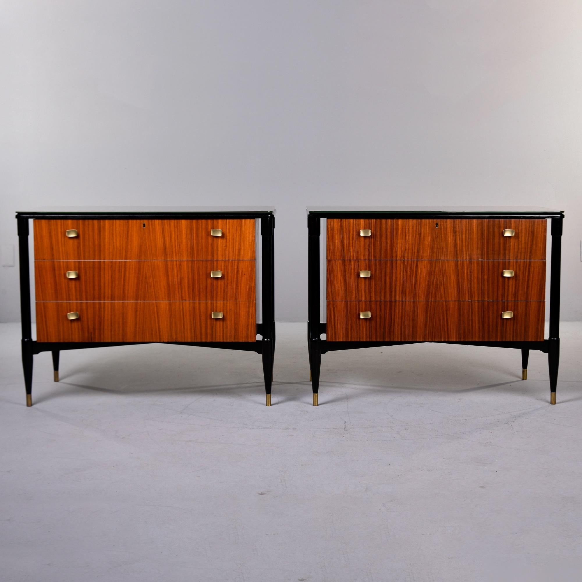 Found in Italy, this pair of mahogany three drawer sides chests date from the late 1950s / early 1960s. Chests are set on floating style black frames with X-form stretchers and brass capped feet. Tops are covered in opaque, off-white glass with