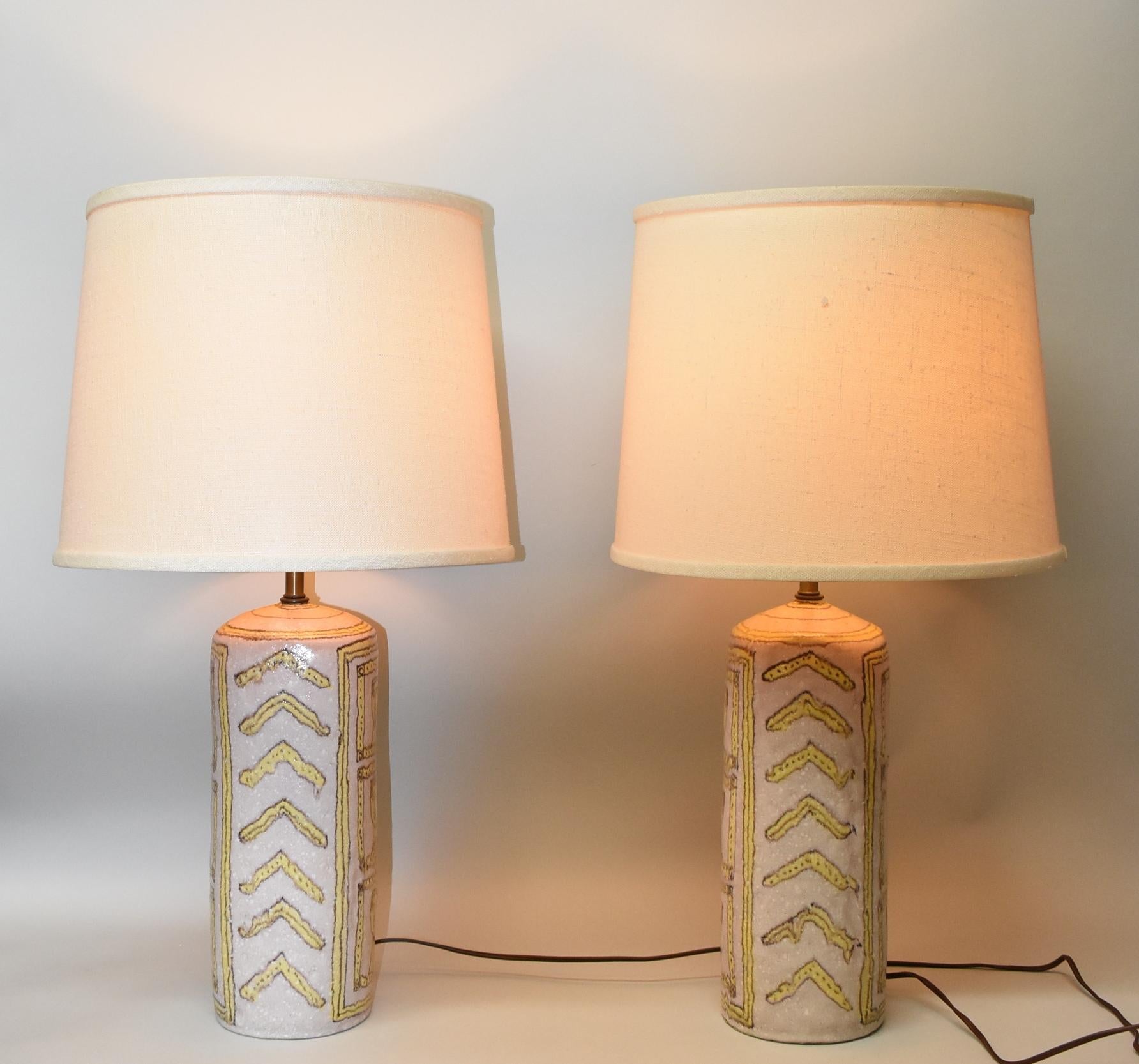 Pair vintage Italian porcelain table lamps by Guido Gambone circa 1950's. Soft mottled shades of yellow and pale purple with designs of faces and arrows. Signed on the bottom. Very good condition. No cracks or chips. Bases measure 5.25