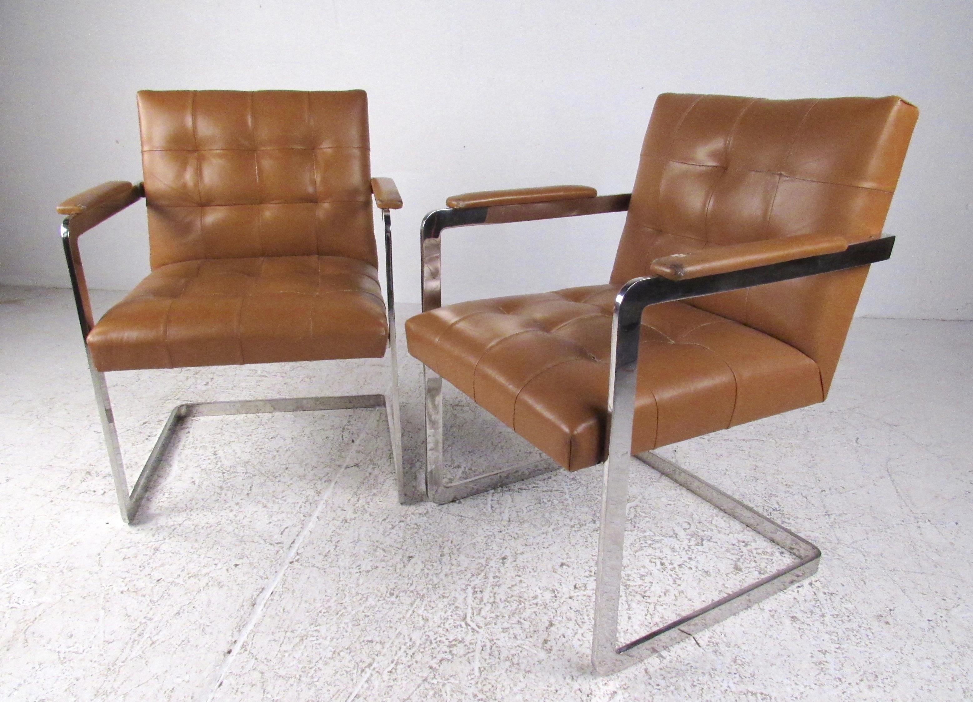 This stylish pair of vintage modern arm chairs feature tufted leather seats and heavy flat chrome frames. Midcentury appeal in the style of Milo Baughman adds striking seating to home or office interiors. Please confirm item location (NY or NJ).