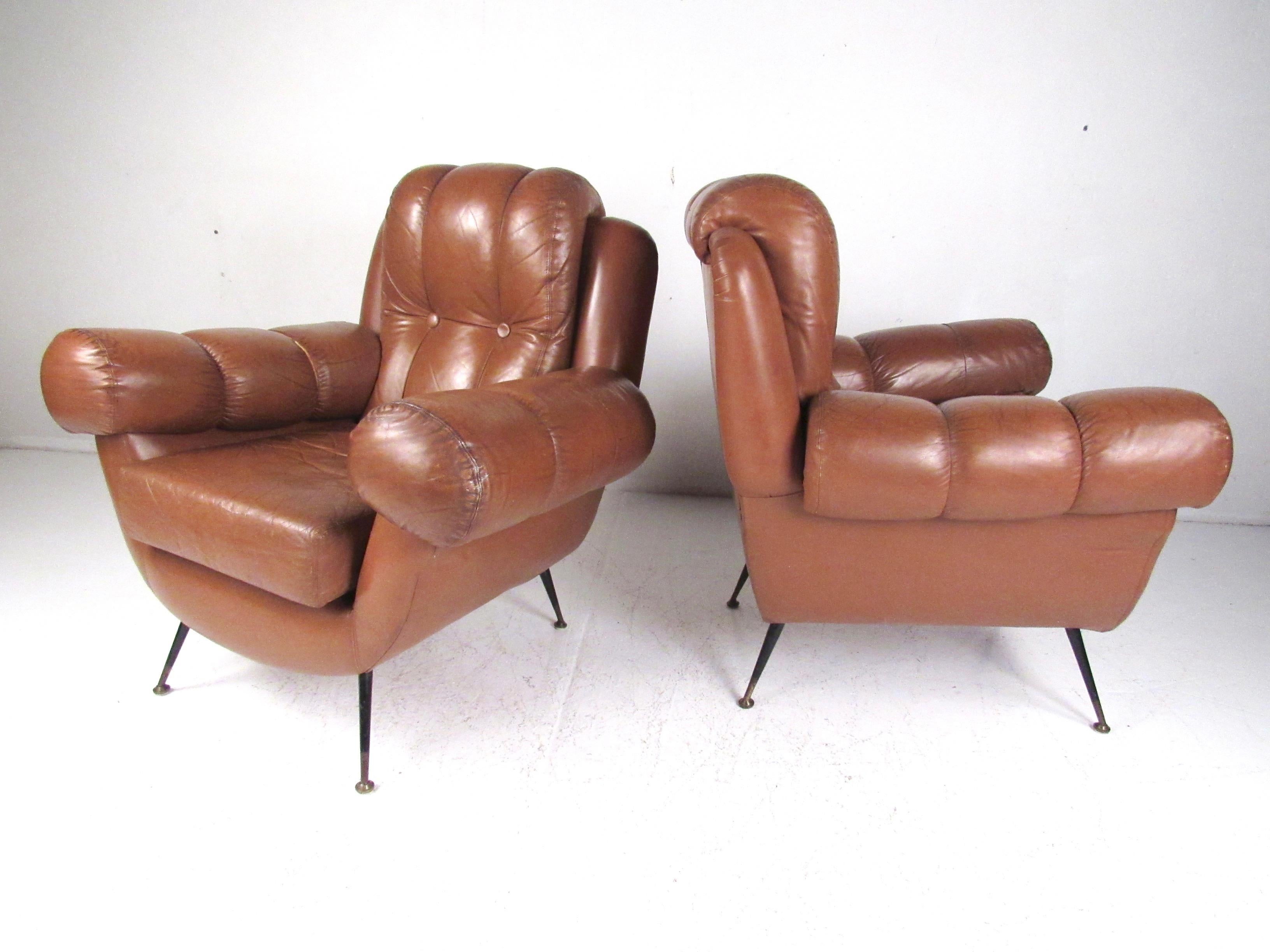 This impressive pair of vintage modern club chairs features tufted leather upholstery, tapered metal legs, and plush padded seats. Unique rounded armrests add to both comfort and Italian modern style of the pair. Please confirm item location (NY or