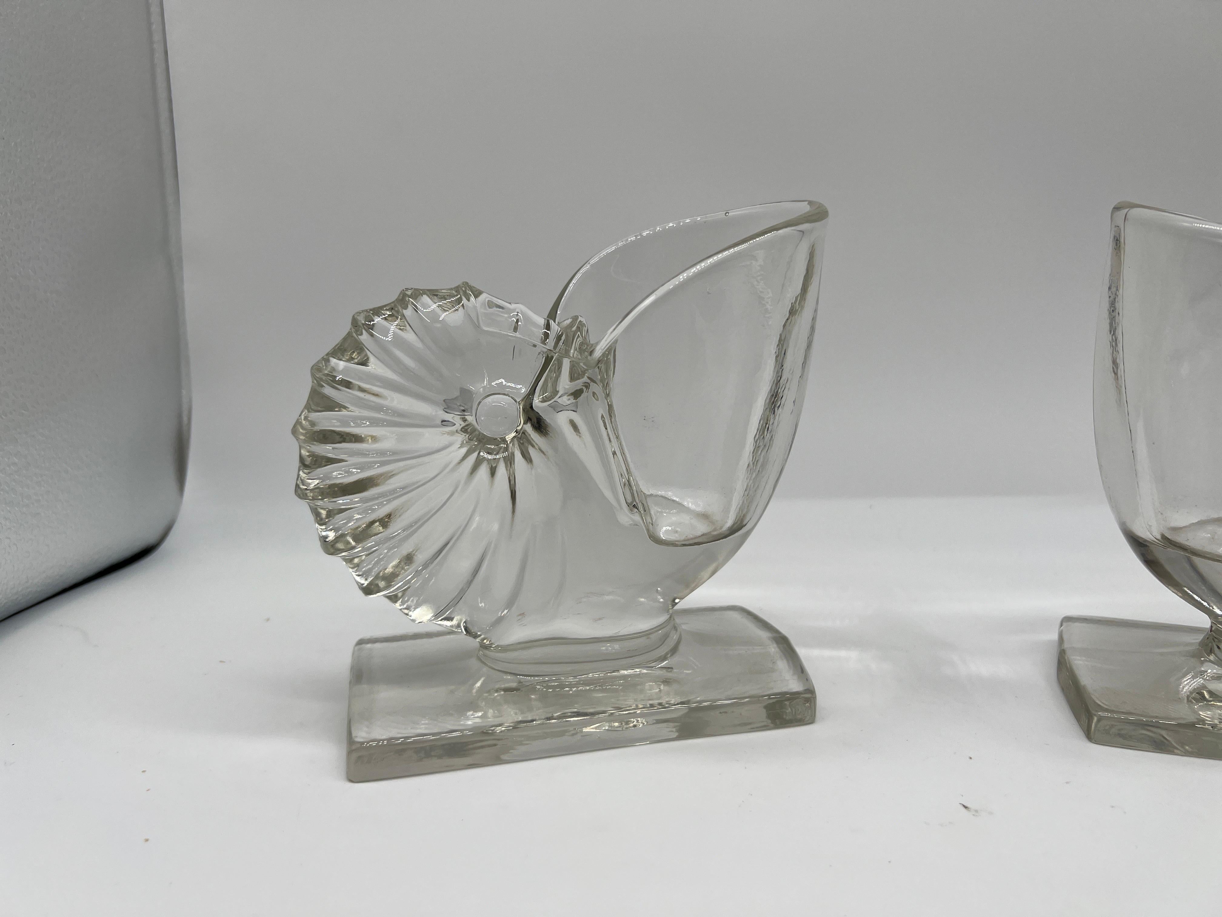 American, circa 1950.

A pair of vintage clear glass nautilus shell book ends or vases. They would be perfect for a pair of succulent plants!

