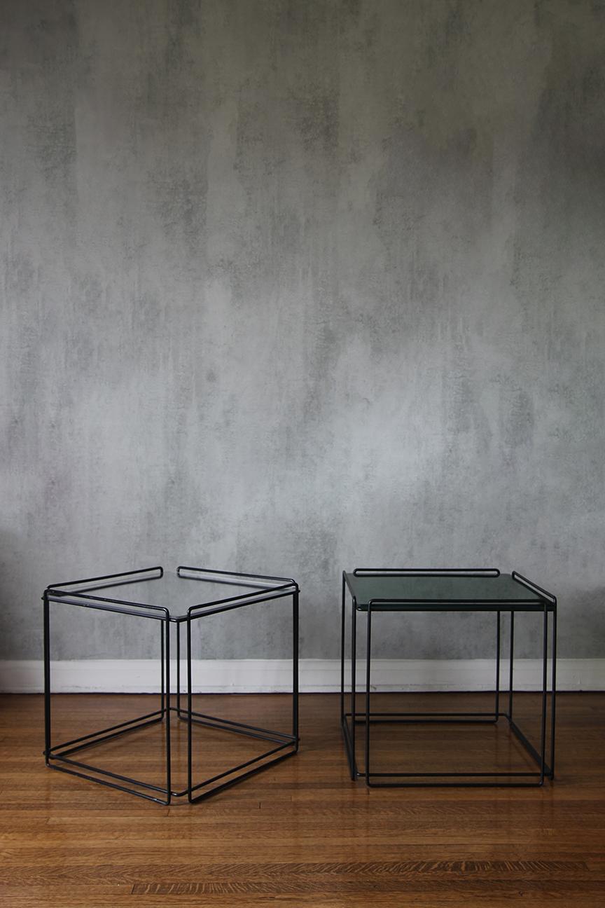 This pair of side tables originates from France and was manufactured in the 1970s by Arrow. They feature a black wire steel frame with two tops: one made of mirror plexiglass and the other of green plexiglass, along with a glass option. Designed by