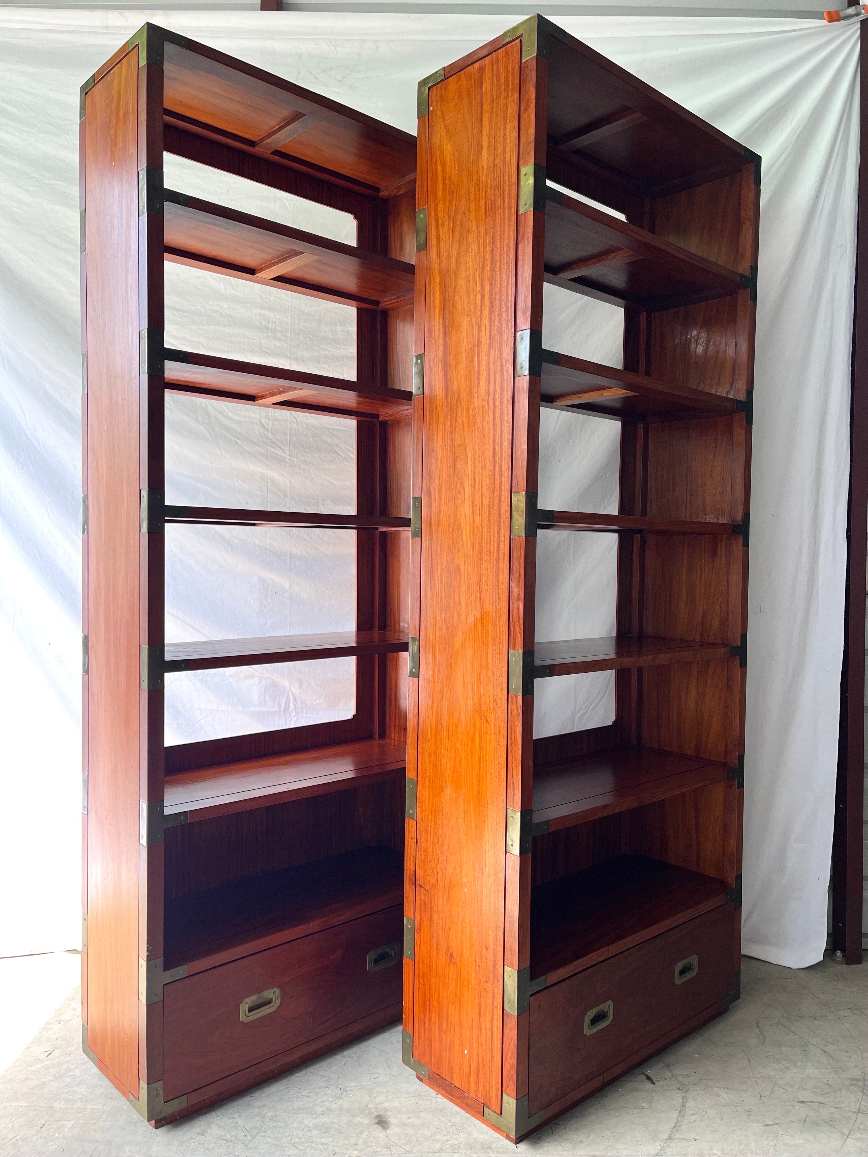 A (coveted) pair of vintage, mid century campaign style floating etagere bookshelves by Dixie Furniture Company. This pair of beautifully crafted brass and wood etageres features six shelves (each ten inches apart), one drawer as well as applied