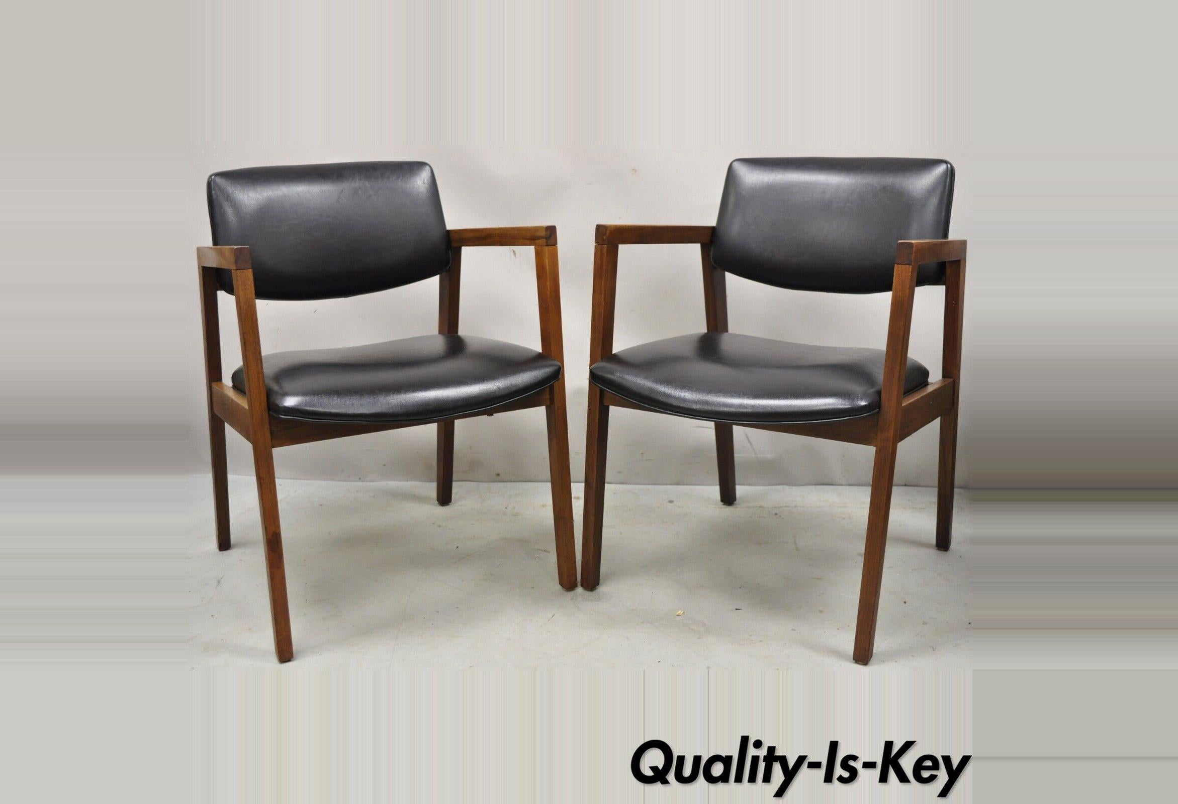 Pair vintage Mid-Century Modern walnut arm chair lounge chair by United Chair Co. Item features black vinyl upholstery, solid wood frames, original labels, clean modernist lines, great style and form. Circa Mid to late 20th Century. Measurements: