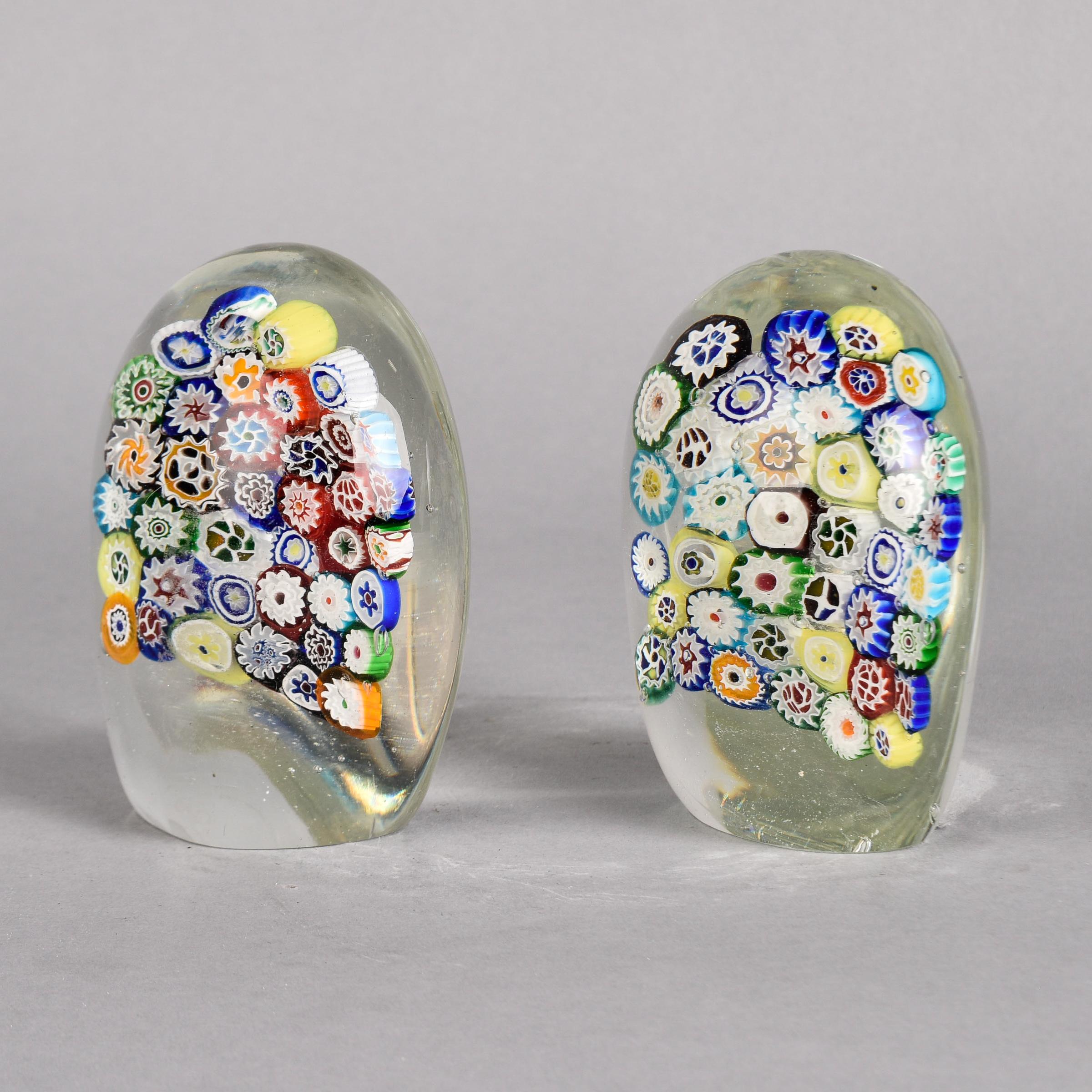 Found in Italy, this pair of millefiori (thousand flowers) bookends have multi color murine flowers suspended in clear, heavy Murano glass. Oval shape with flat base and flat inside edge that supports the books. Sold and priced as a pair. Makes a