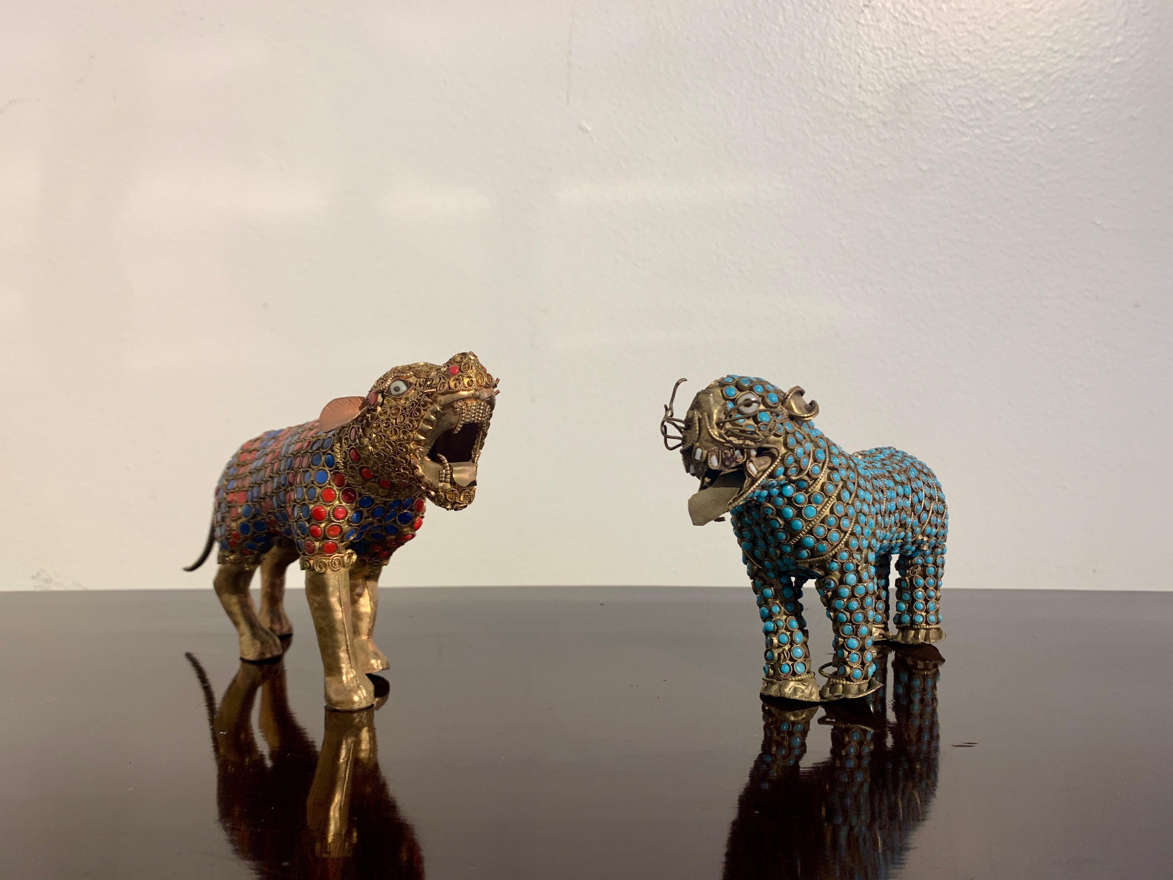 A delightful near pair of vintage Nepalese glass studded brass tigers, circa 1970's, Nepal.

One tiger standing foursquare, head extended, mouth open in a roar, with brass whiskers to the face. The body studded with blue glass bead imitating