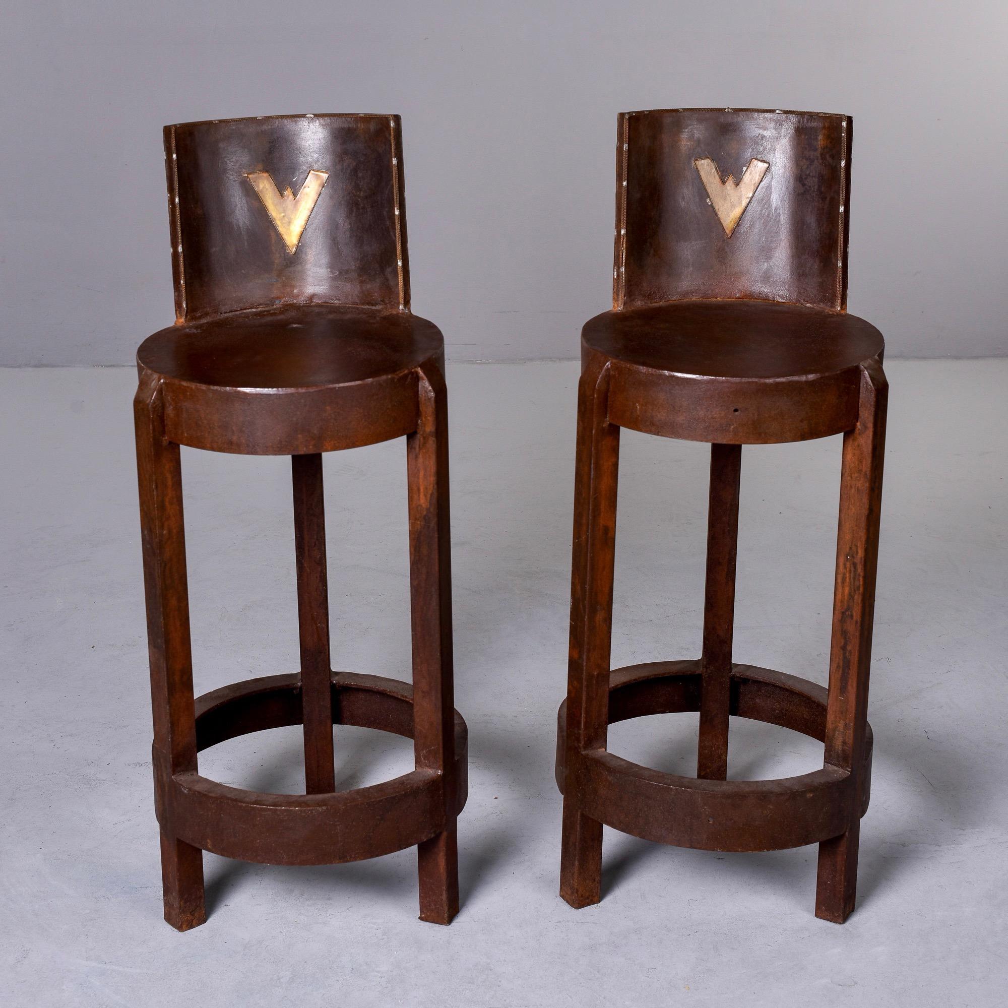 Circa 1980s pair of industrial style bar height stools from Norway. These three legged tools are made of iron with rust colored finish - note - this is not a rusted finish but a rust colored finish. Round seats are 29.5” from floor. Foot rests at