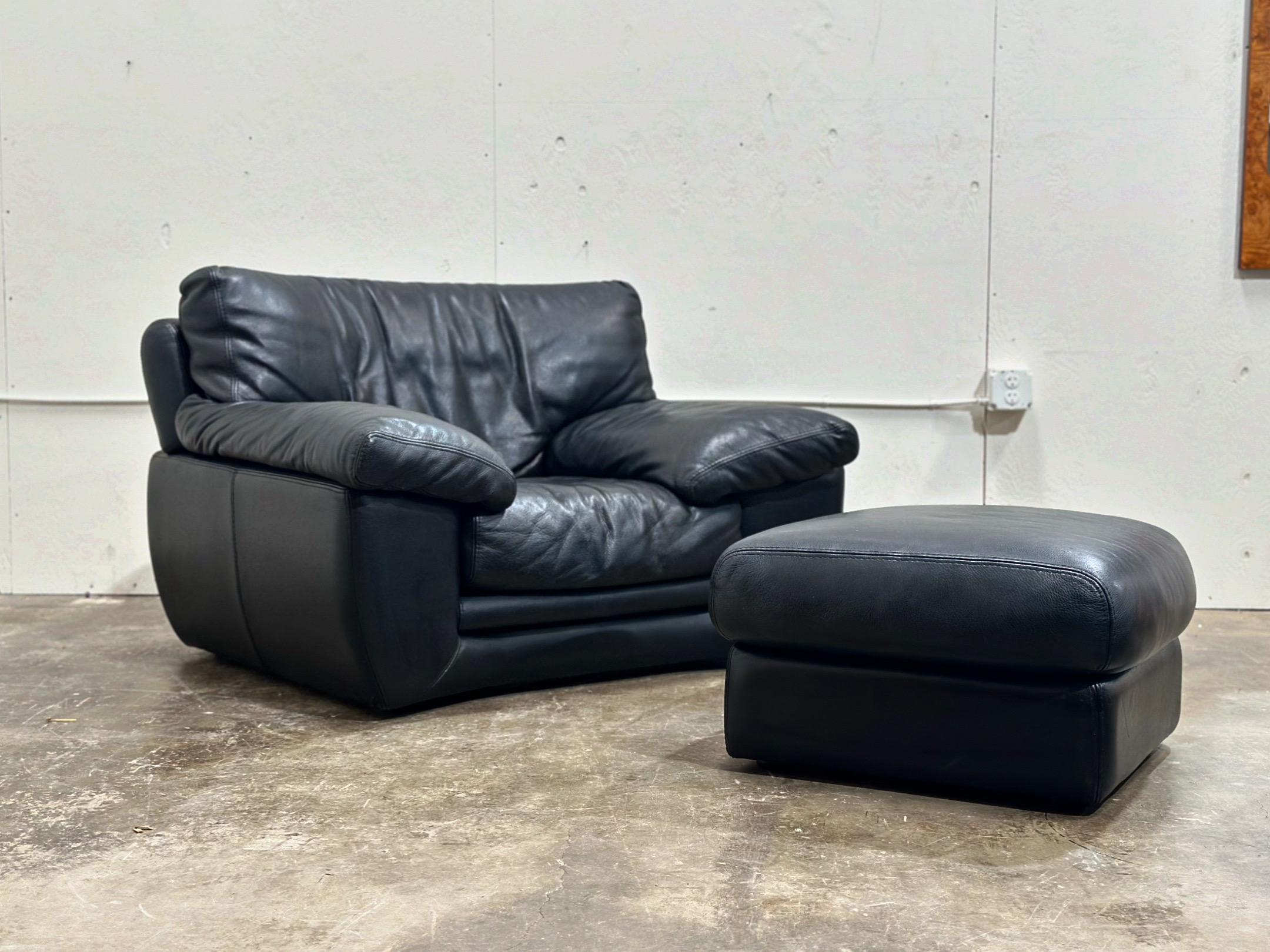 Exquisite pair of vintage post modern leather lounge chairs with ottomans by Roche Bobois, France circa late 1980s. Striking silhouette and opulent comfort. The full grain black leather has aged to perfection. Stacked curved backs make these chairs