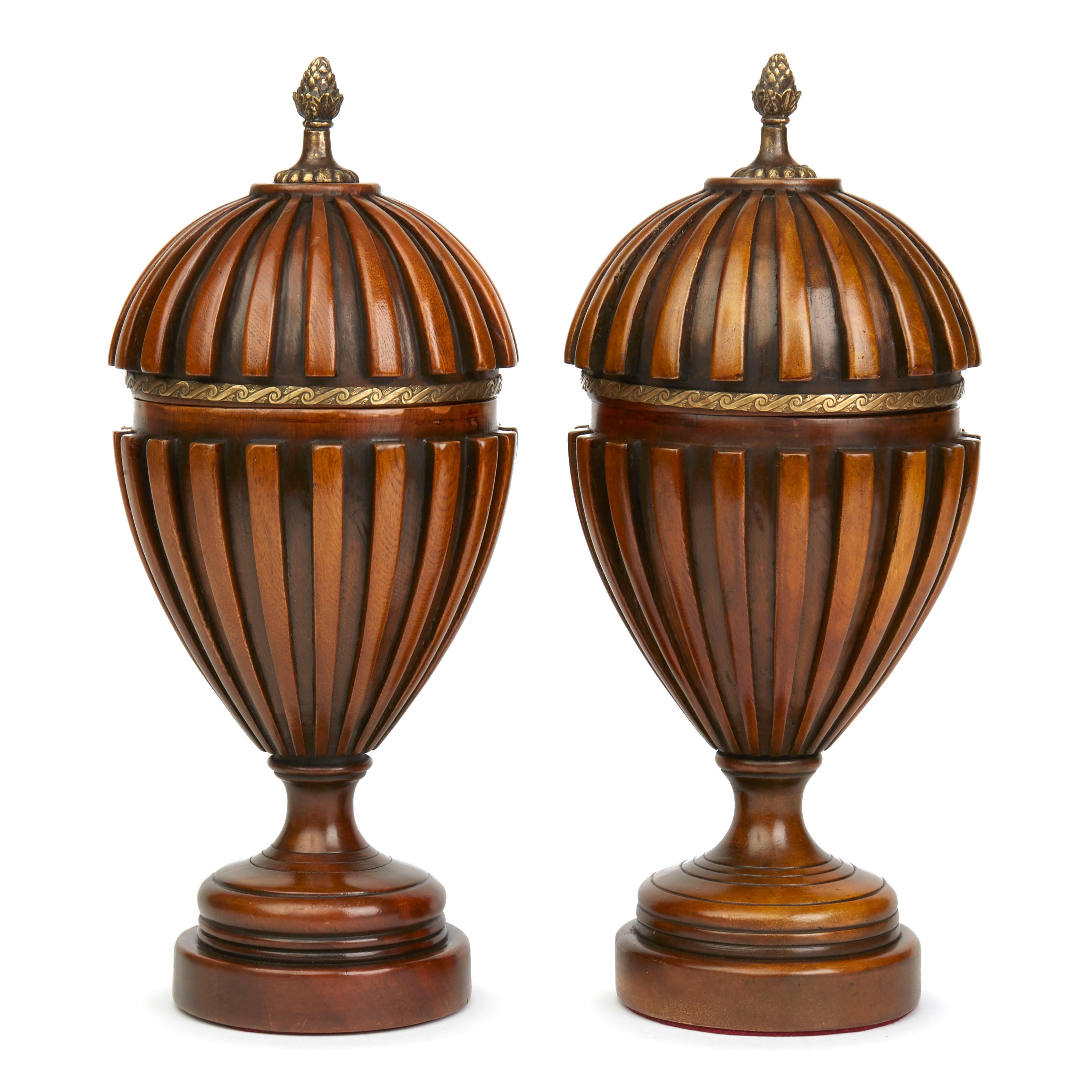 A stylish pair Adam Style bronze metal mounted lidded wooden pedestal urns with a carved ribbed design to the cover and body. Supported on a rounded pedestal foot the urns have a cherry wood patina and are not marked. Possibly Italian.

  