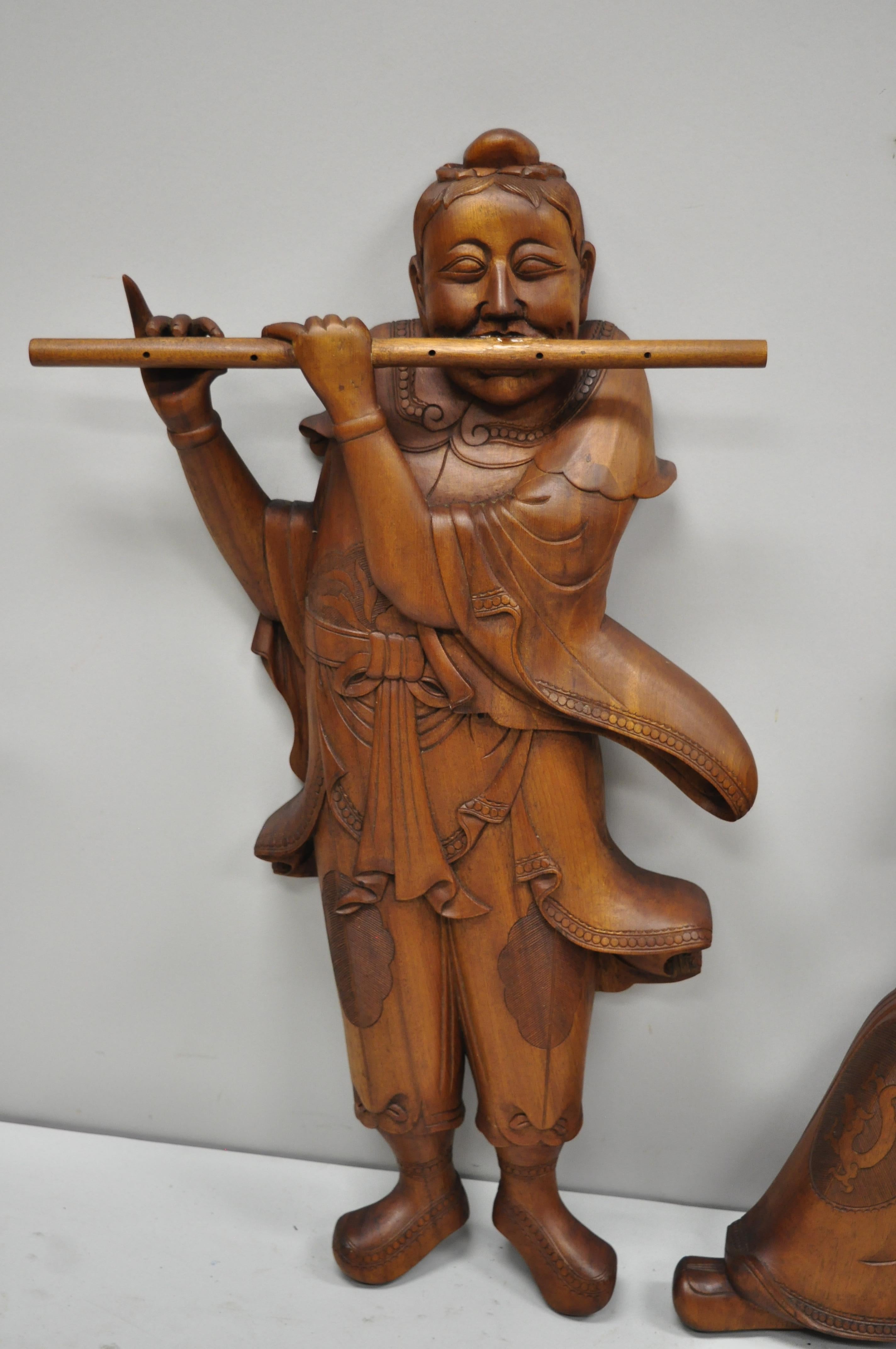 Pair of vintage Ricardo Lynn carved teak wood oriental figures flute player Wiseman. Items feature large impressive form, flute playing woman, wiseman seated on garden stool, remarkable details, solid teak wood construction, beautiful wood grain,