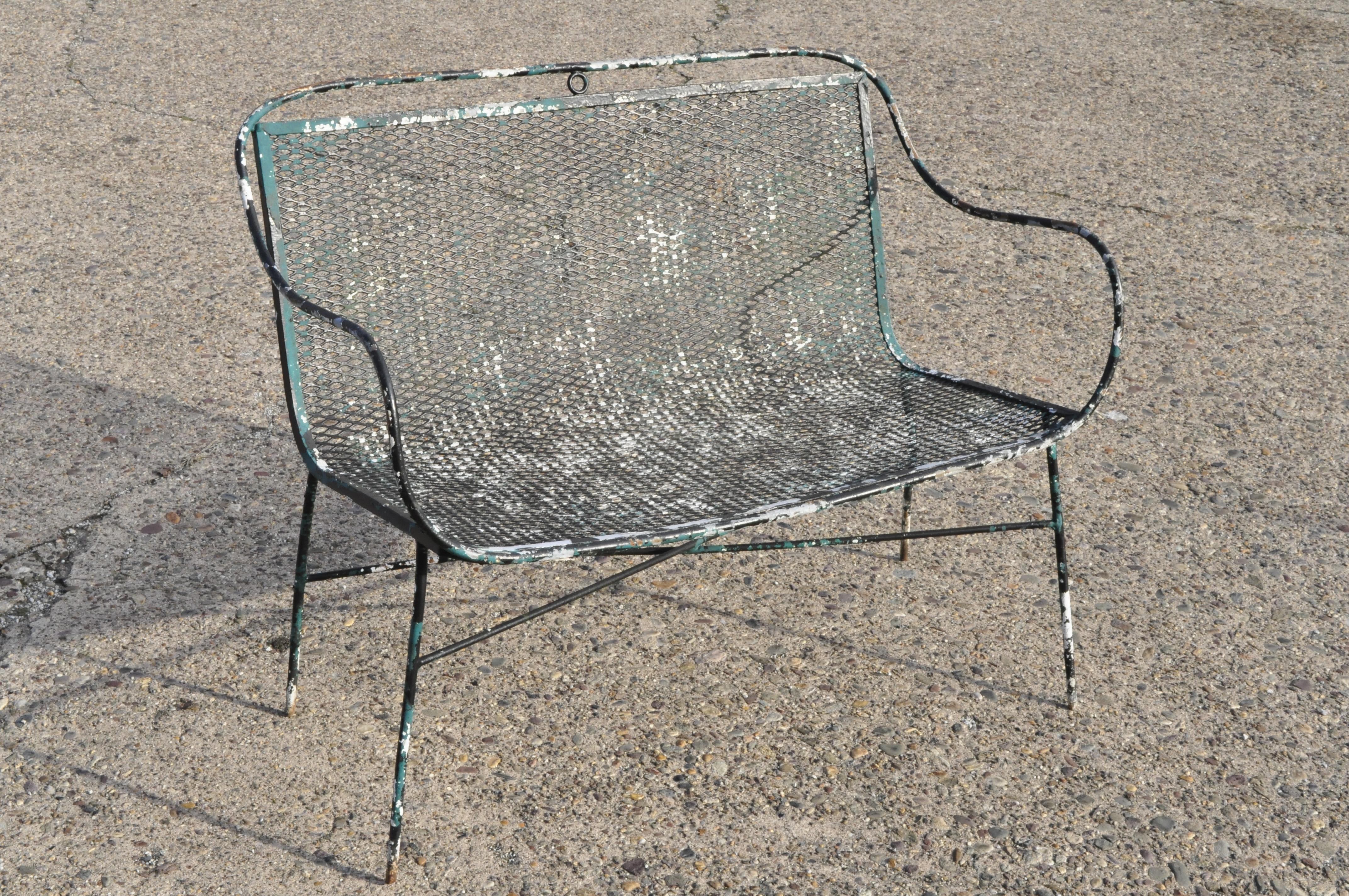 Pair of vintage Salterini style Mid-Century Modern wrought iron settee bench. Item metal mesh seat and back, wrought iron construction, sleek sculptural form, circa mid-20th century. Measurements: 31.5