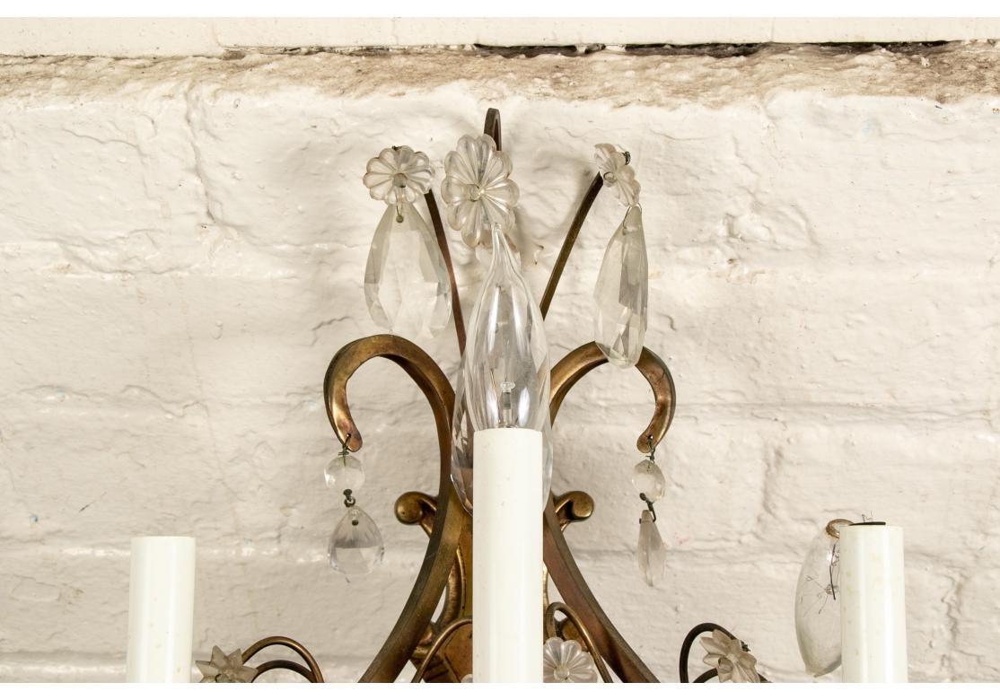 Three electric lights with candle sockets on scrolled frames and shaped backs. Overall crystal drops and rosettes. 

Dimensions: H. 22