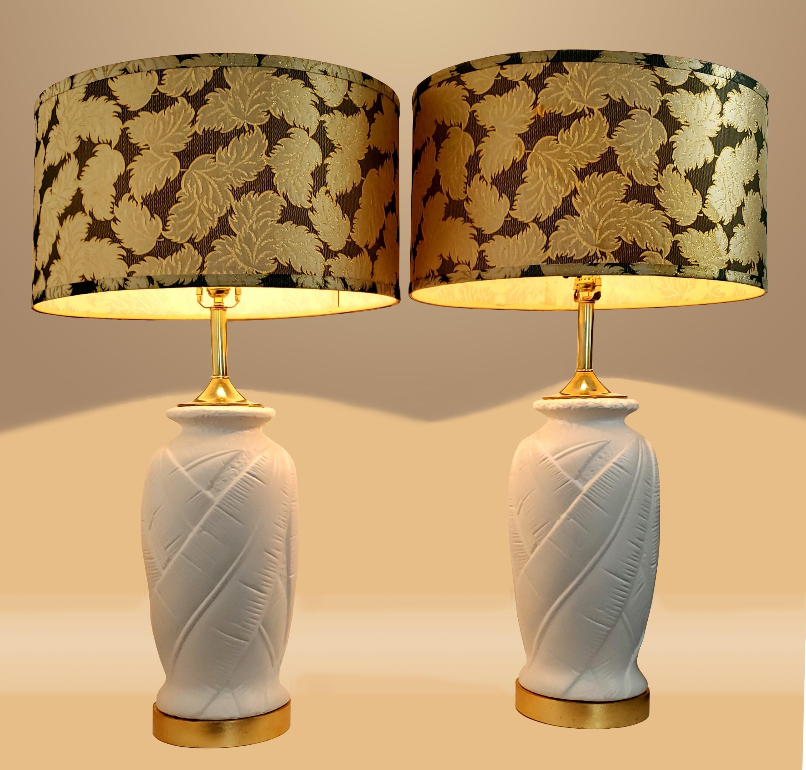 Pair of vintage restored white plaster palm tree leaf lamps with decorative vintage lamp shades, circa 1980. These lamps were completely disassembled, professionally primed and painted white with new gold leaf on the wooded bases.
Vintage lamp