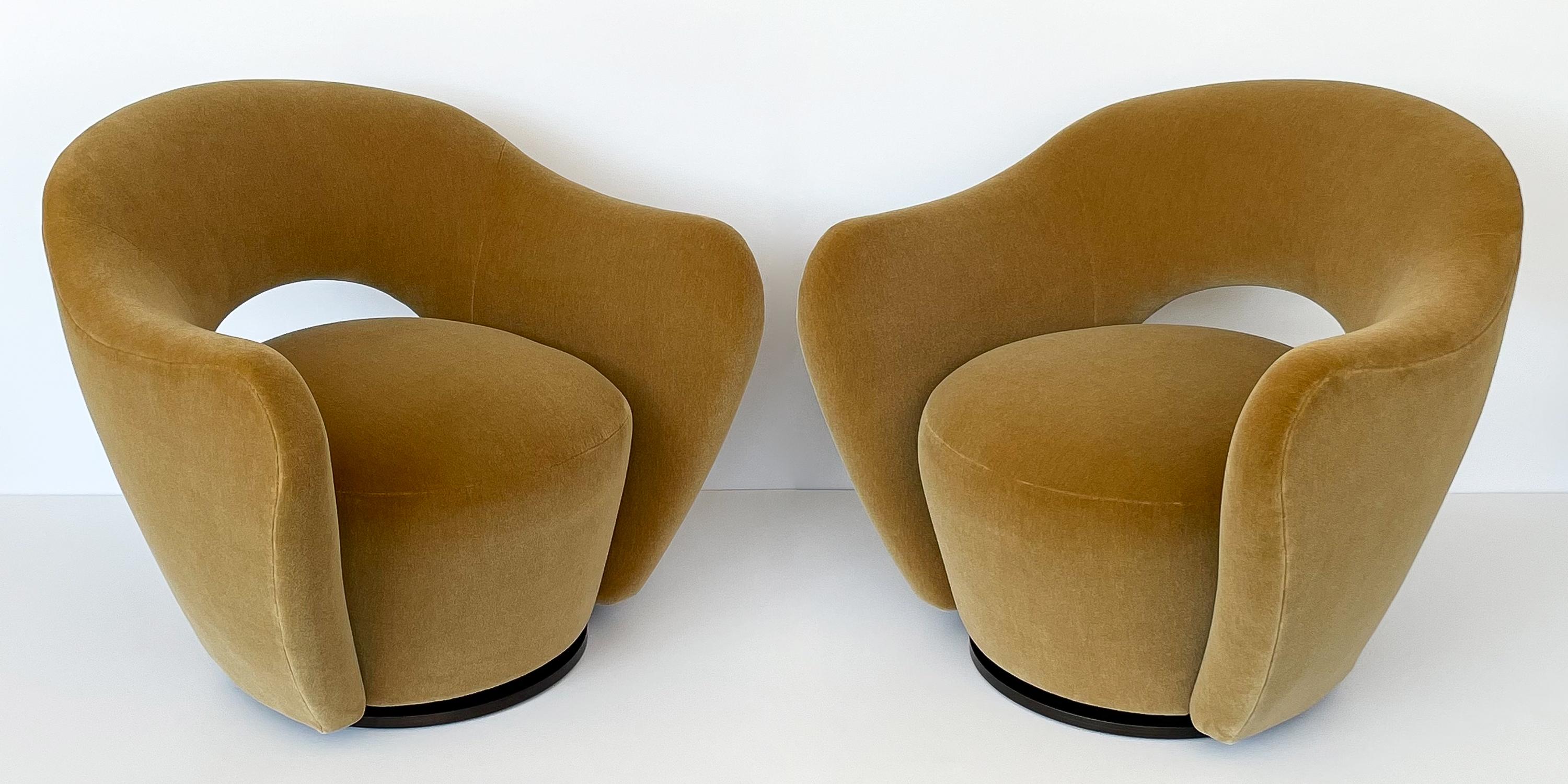 Pair of Vladimir Kagan open back swivel lounge chairs for Directional. Newly upholstered in a gorgeous and sophisticated camel / caramel colored plush mohair with all new foam throughout. Newly finished dark walnut wood pedestal bases with 360