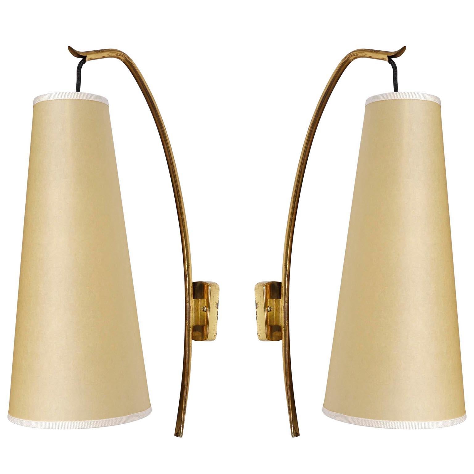 A pair of Mid-Century Modern wall lamps model 'Soldanella' no. 4331/1. by J.T. Kalmar, Austria, manufactured ca. 1960 (1950s - 1960s). 
A brass wall arm holds a lampshade made of parchment. The lights are in very good condition and ready for use.