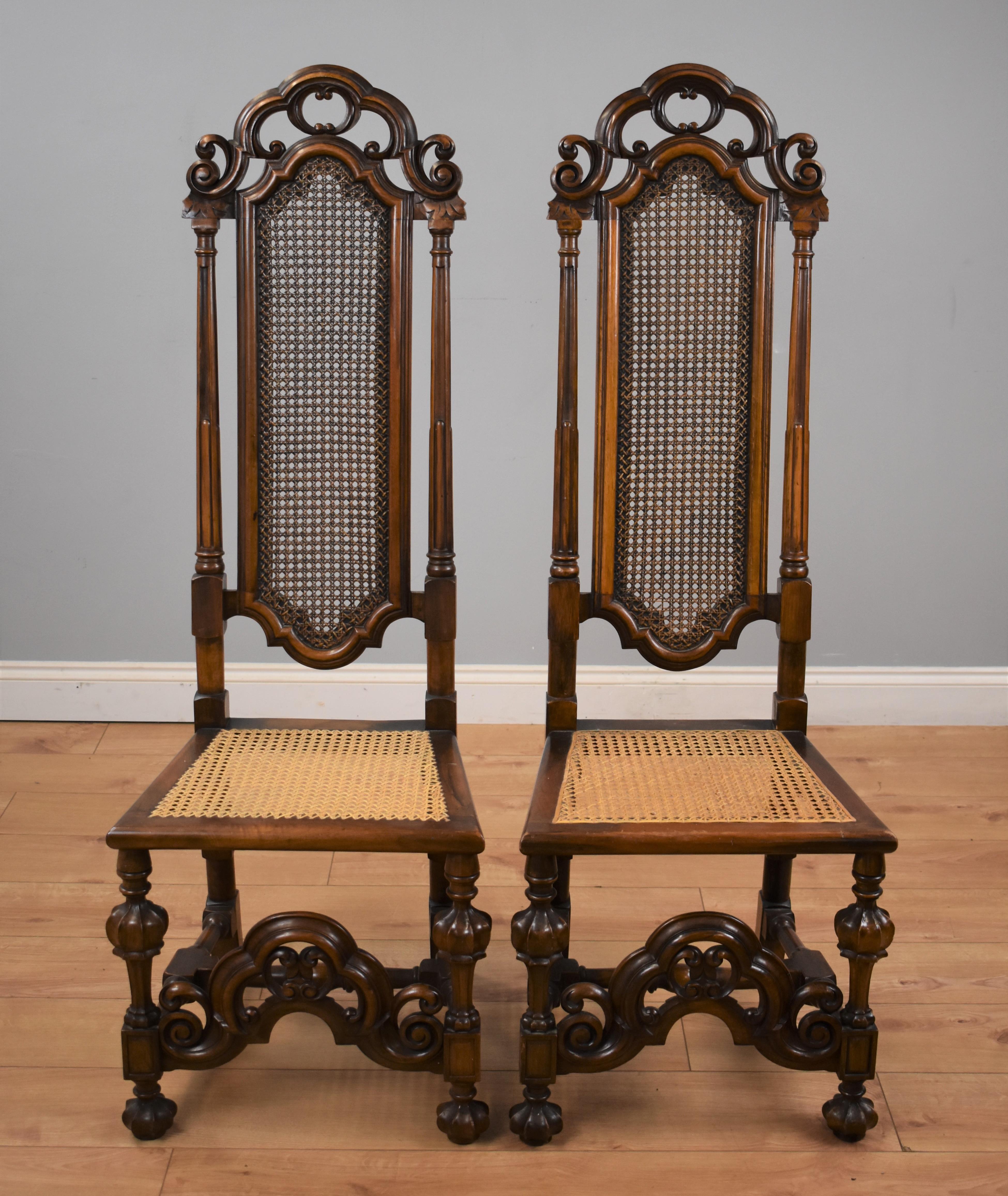 Pair of Carolean style walnut high back chairs with cane work seats and back panel with carved lower rail.
