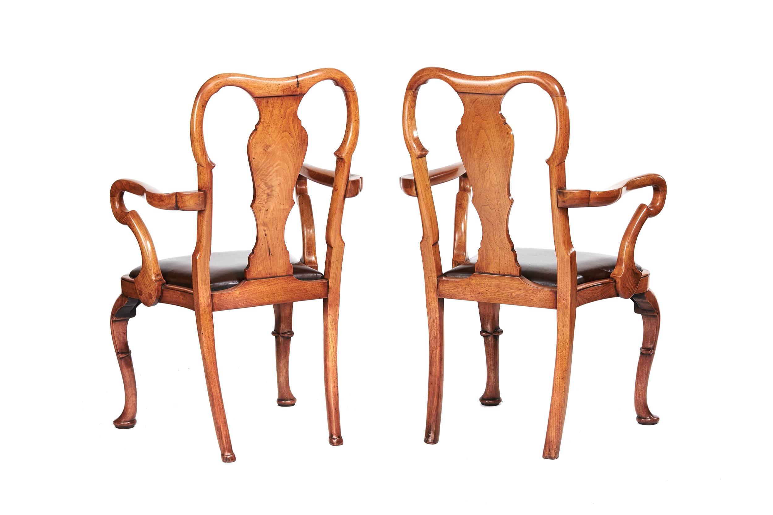 Pair Walnut Elbow Chairs in the Queen Anne Style circa 1920s
Queen Anne Shaped Backs, 
Shepherds Crook Shaped Elbows, 
Brown Leather drop in seats, 
Cabriole shaped legs with scroll carved detail
Recently Polished
Dimensions: Seat Height:48cm x
