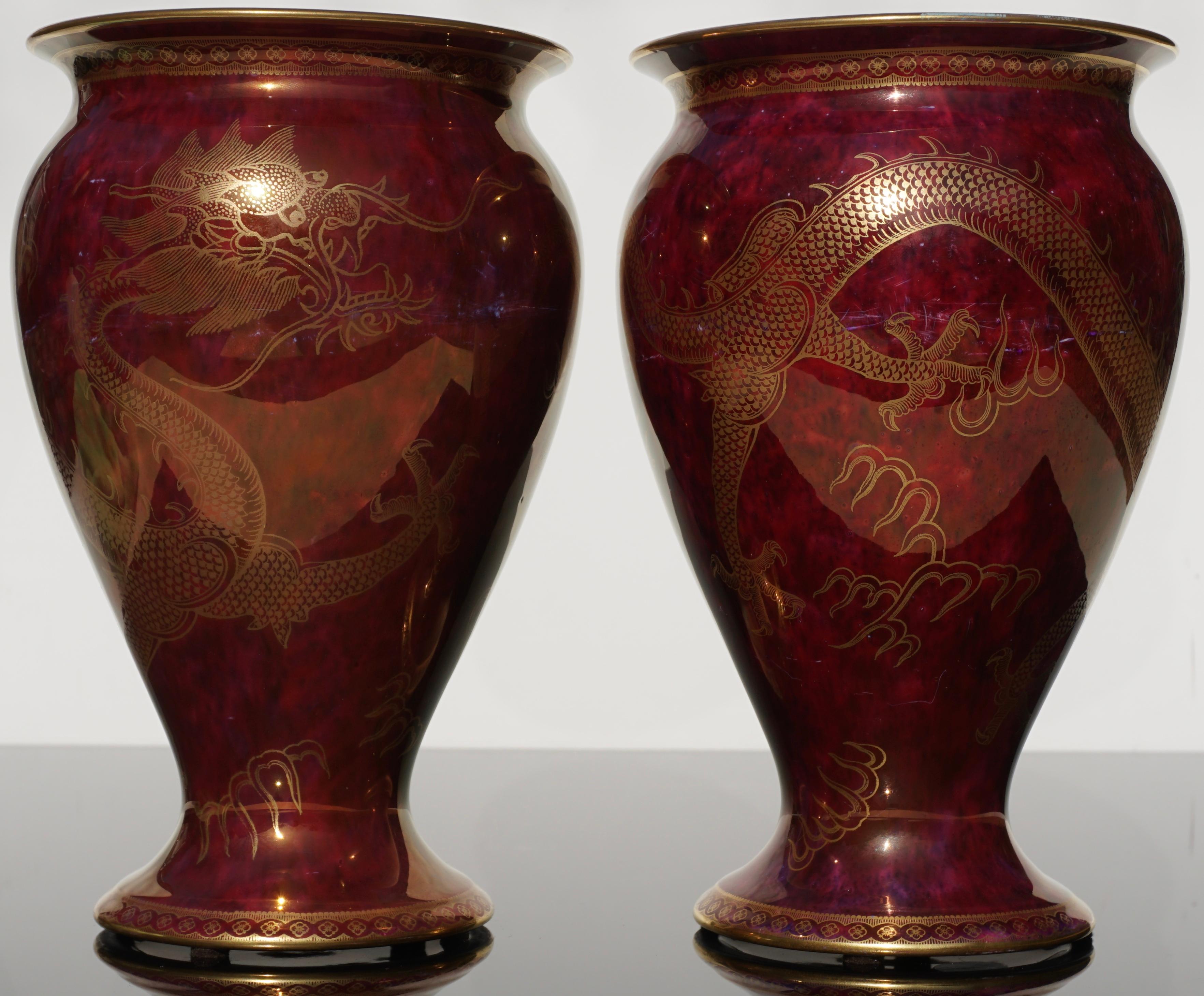 A matching pair of Wedgwood Lustre vases decorated with gilded dragon motif against a mottled scarlet lustre background on the exterior, and daylight lustre interiors further decorated with three colorful butterflies with gilded trim and stylized