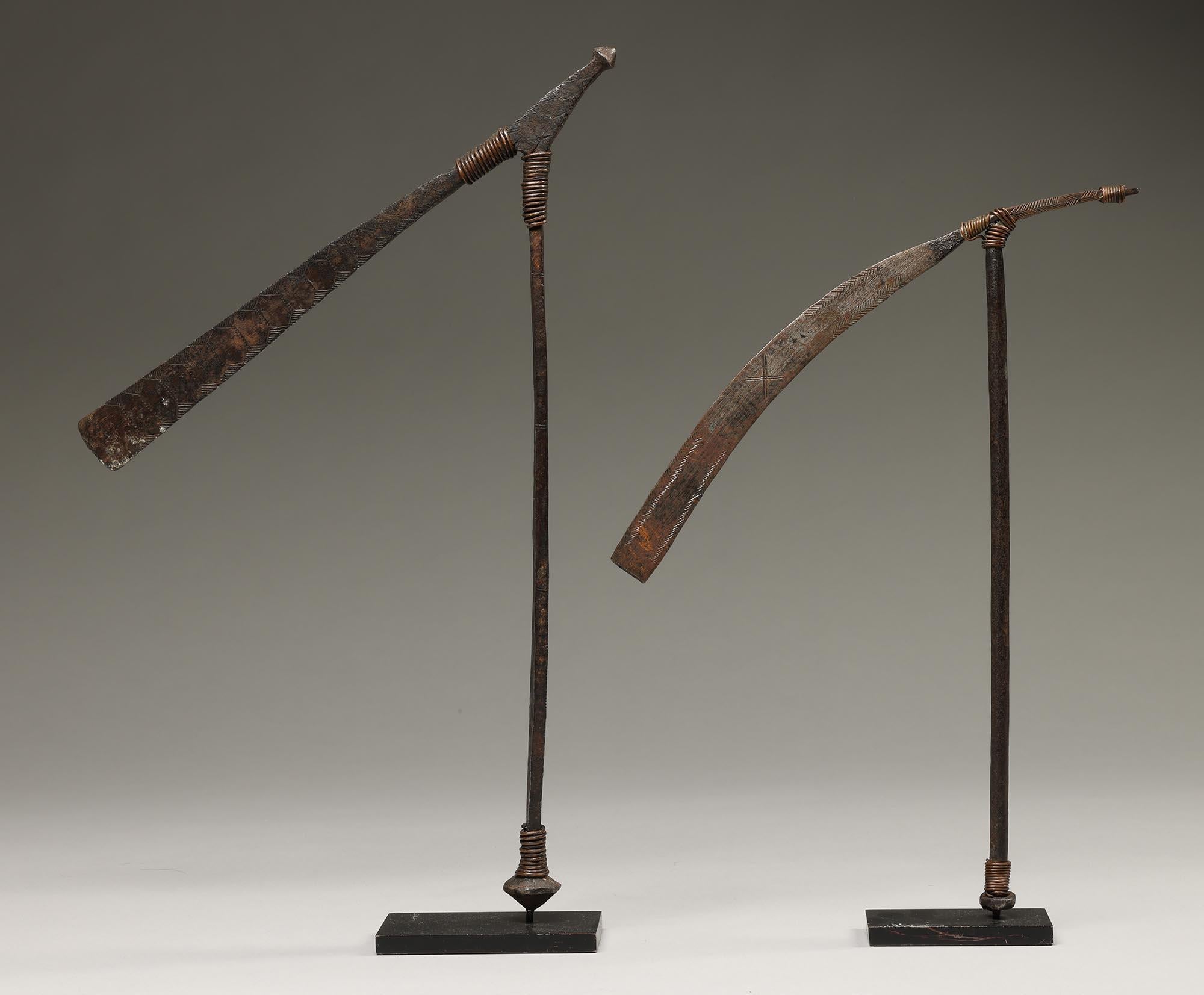 A pair of West African incised iron and copper wire axe form currency pieces. On custom mounts.  In the form of a ritual axe, which in many parts of Africa was carried over the shoulder as a prestige item.

They are in good condition, appropriate