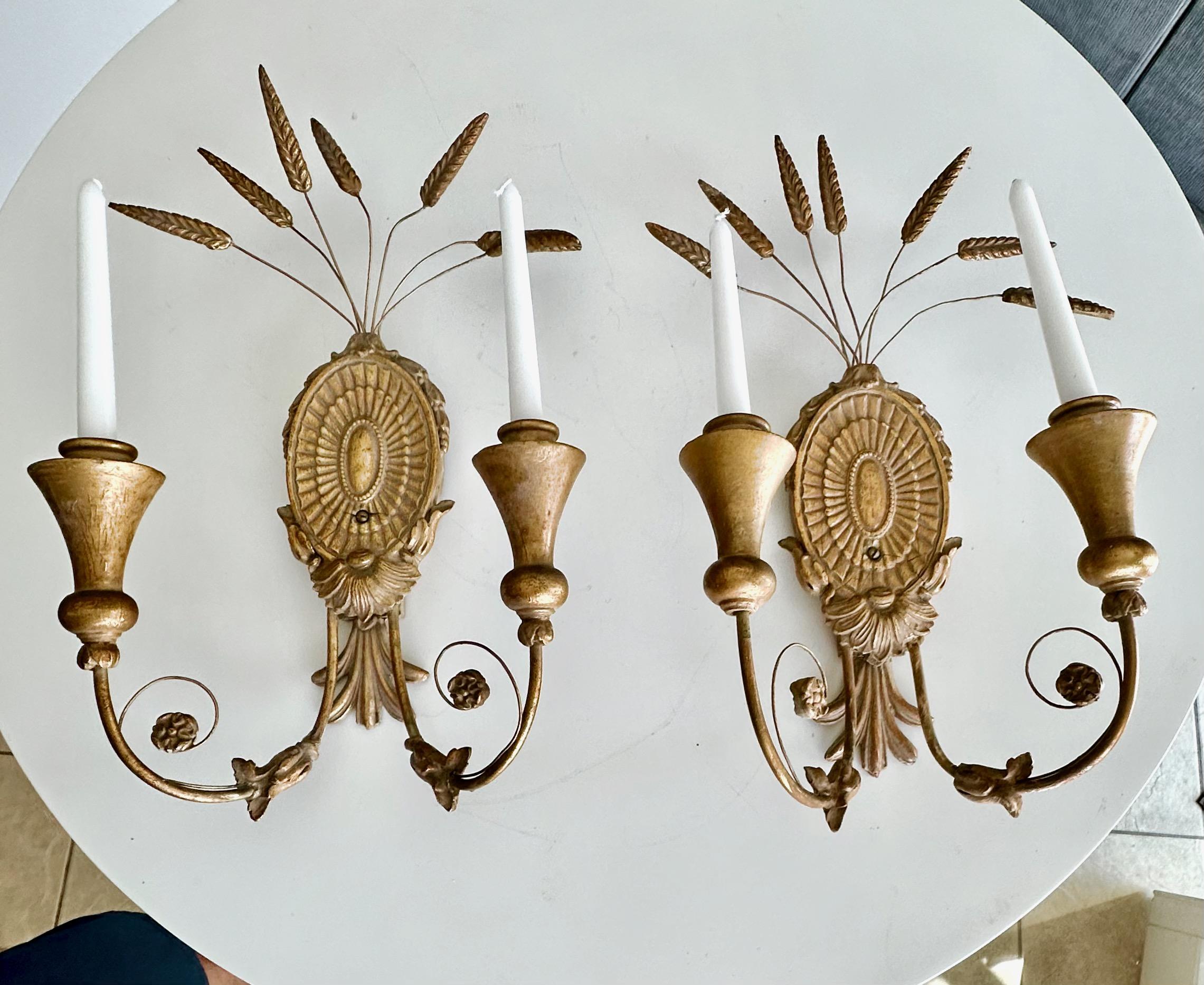 Pareja de candelabros de pared de dos brazos de madera dorada y escayola. Utiliza velas no electrificadas. 
