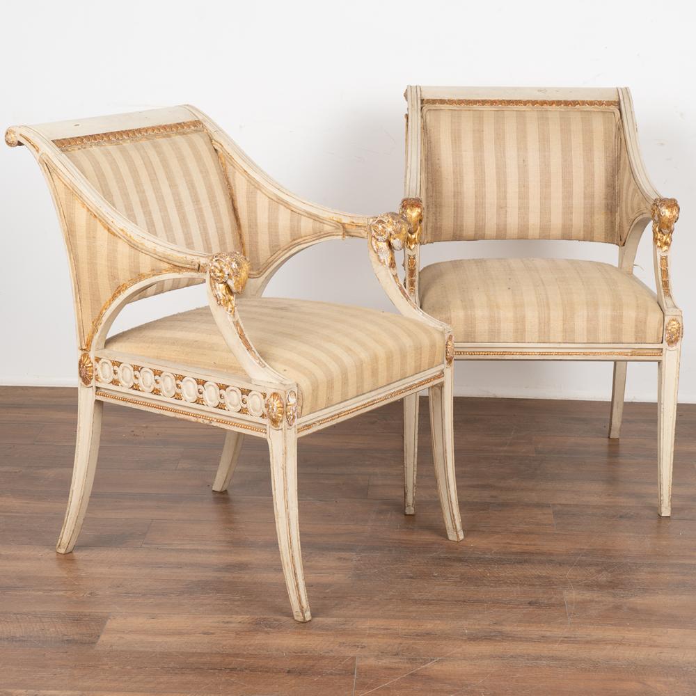 Pair, attractive Swedish Louis XVI painted arm chairs with rams head carvings on arms.
Tapered, gently curved legs, beaded trim and carved accents along seat and back.
White painted finish and gold accents with gentle distressing add an aged