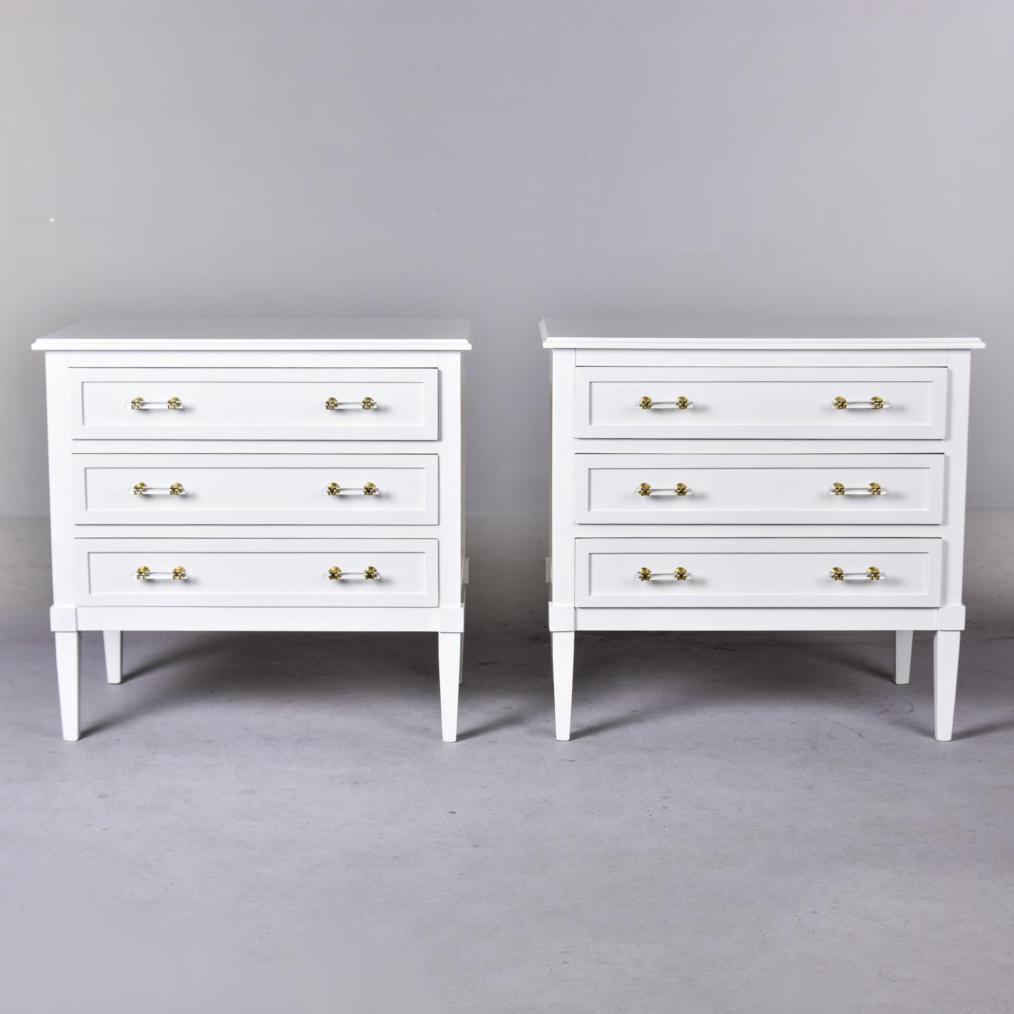 This pair of three drawer chests is new and was custom made to our specifications by an English cabinet maker. Classic shape with tapered legs and a white painted finish with lucite and brass hardware to keep the look light. Sold and priced as a