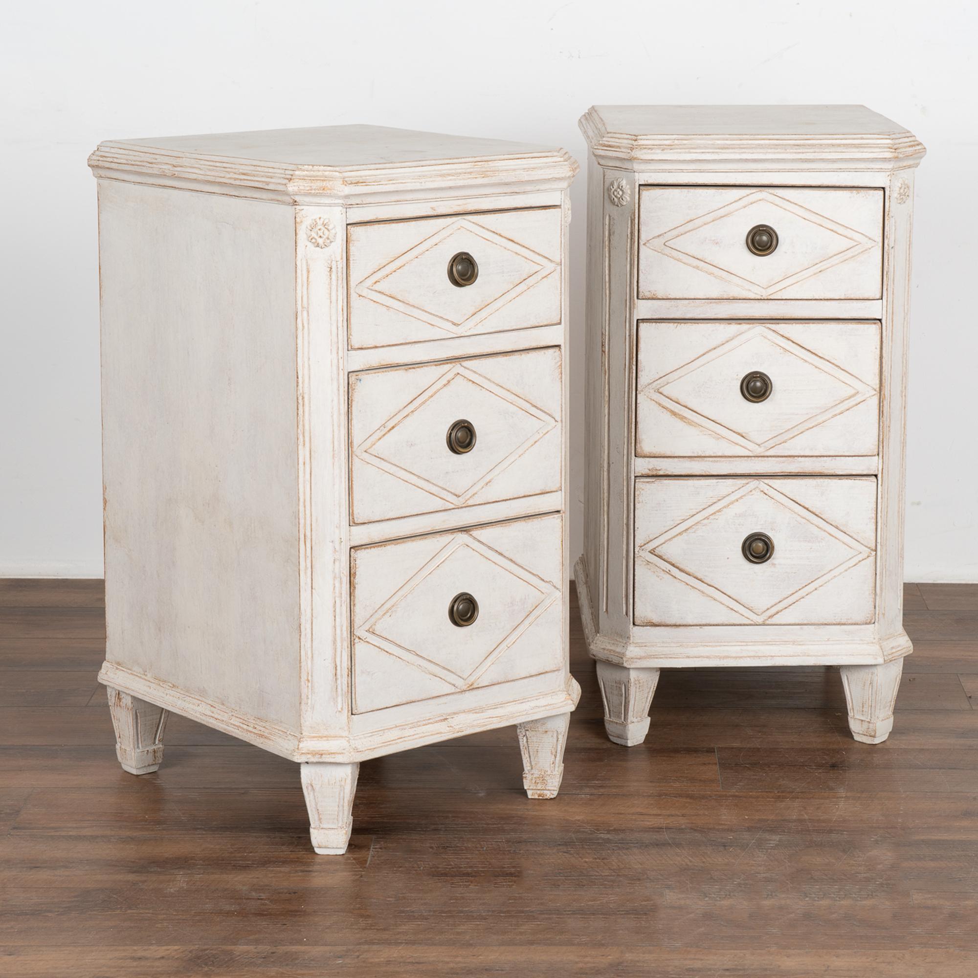 Pair, Gustavian style small chest of drawers with fluted canted sides and fluted tapered feet perfect to use as nightstands or small side tables. 
The three drawers each have a single brass pull and decorative diamond shaped panels, a favorite