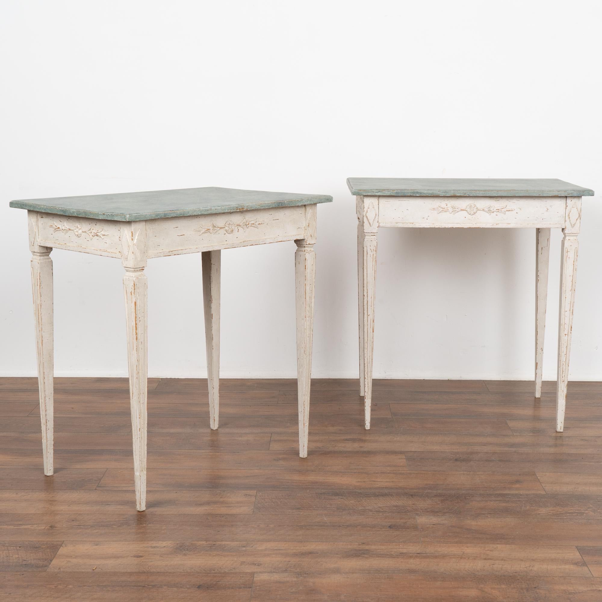 Pair, Gustavian side tables with slender tapered fluted legs and delicate carving along skirt. 
Restored, later professionally painted in layered shades of white and lightly distressed to fit the age and grace of this lovely table. Top is painted in