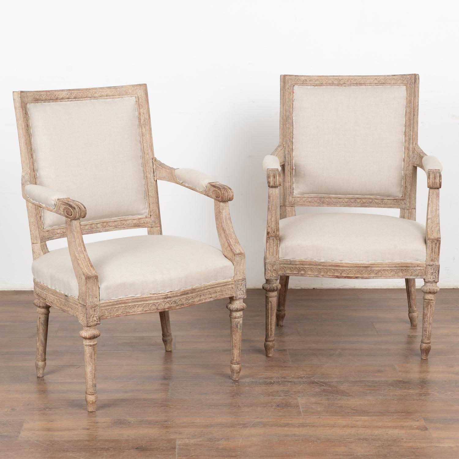 Pair, Swedish white painted armchairs with carved details along edges, top of back and bottom of seat; turned fluted legs.
The newer, professionally applied antique white painted finish is typical of the 1900's era in Sweden. It has been distressed