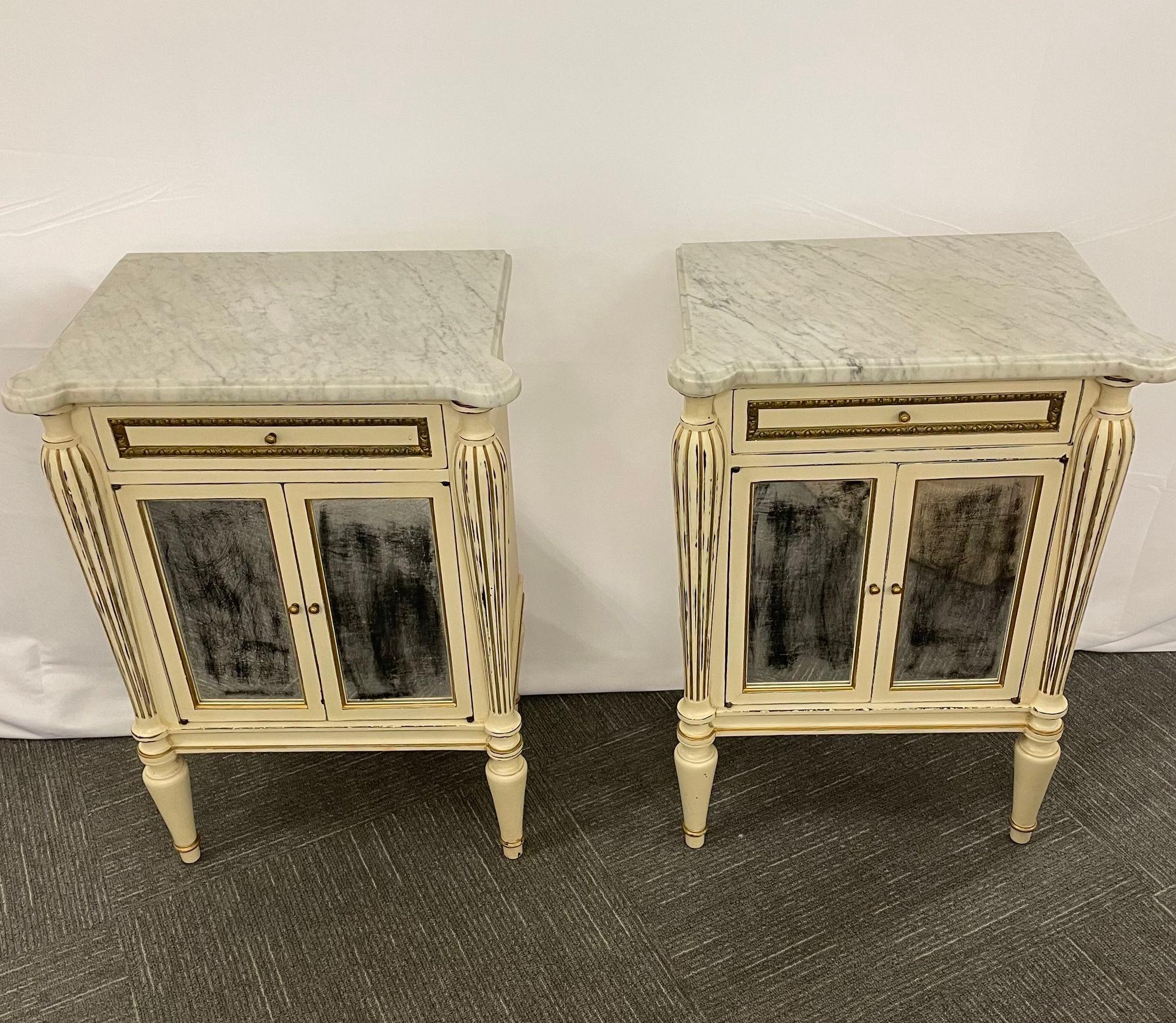Pair of Painted Marble Top End Tables Distressed Mirrored Cabinets Stamped Jansen
 
Pair of French white distress-painted cabinets, circa 1950s, the white marble over a conforming case fitted with a single drawer with bronze banding, over a mylar