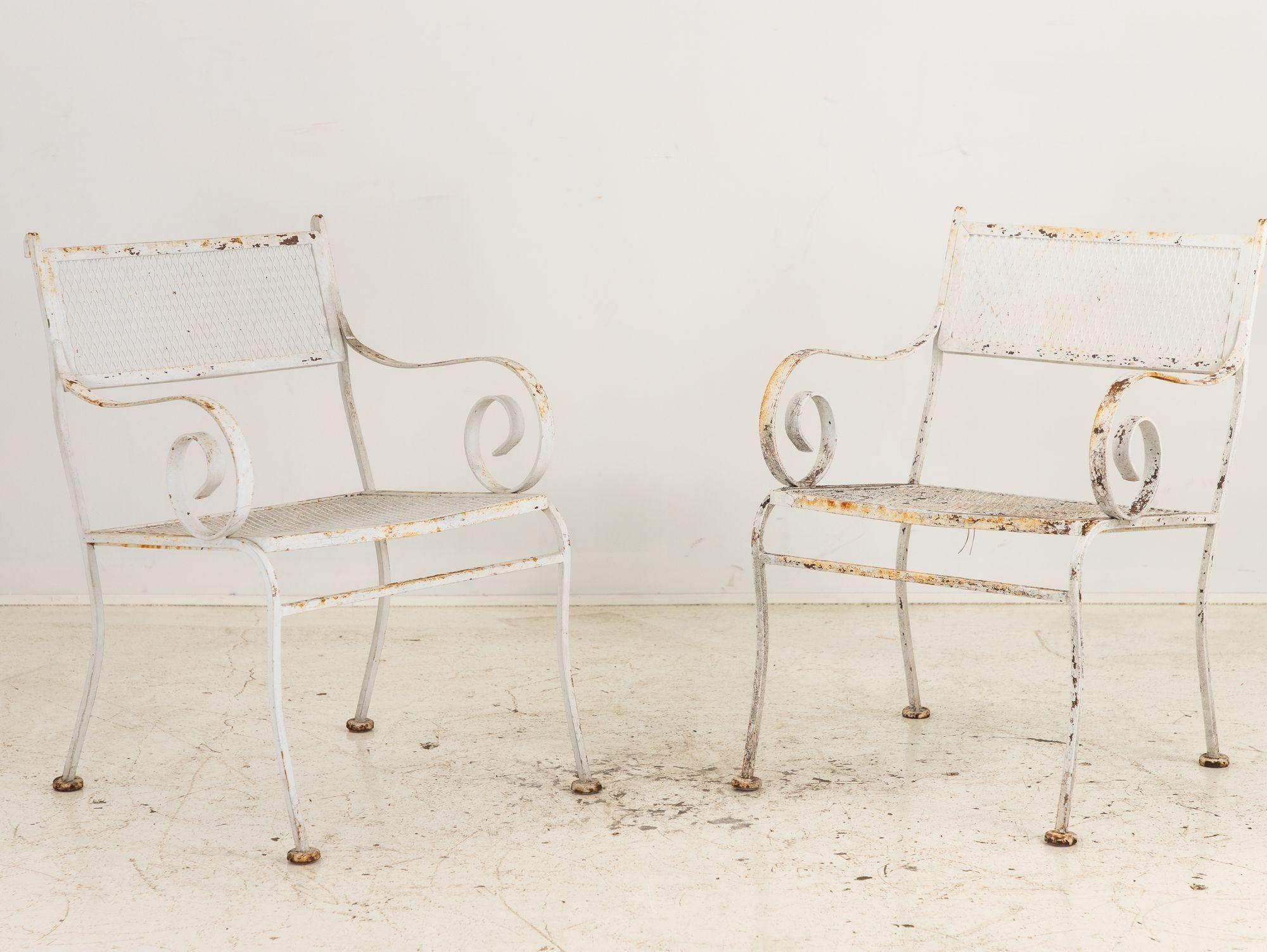 Crafted in the vibrant era of 1950s America, this pair of white-painted iron chairs embodies classic elegance and enduring style. With gracefully scrolled arms and splay legs, they exude sophistication reminiscent of the iconic designs of Woodard