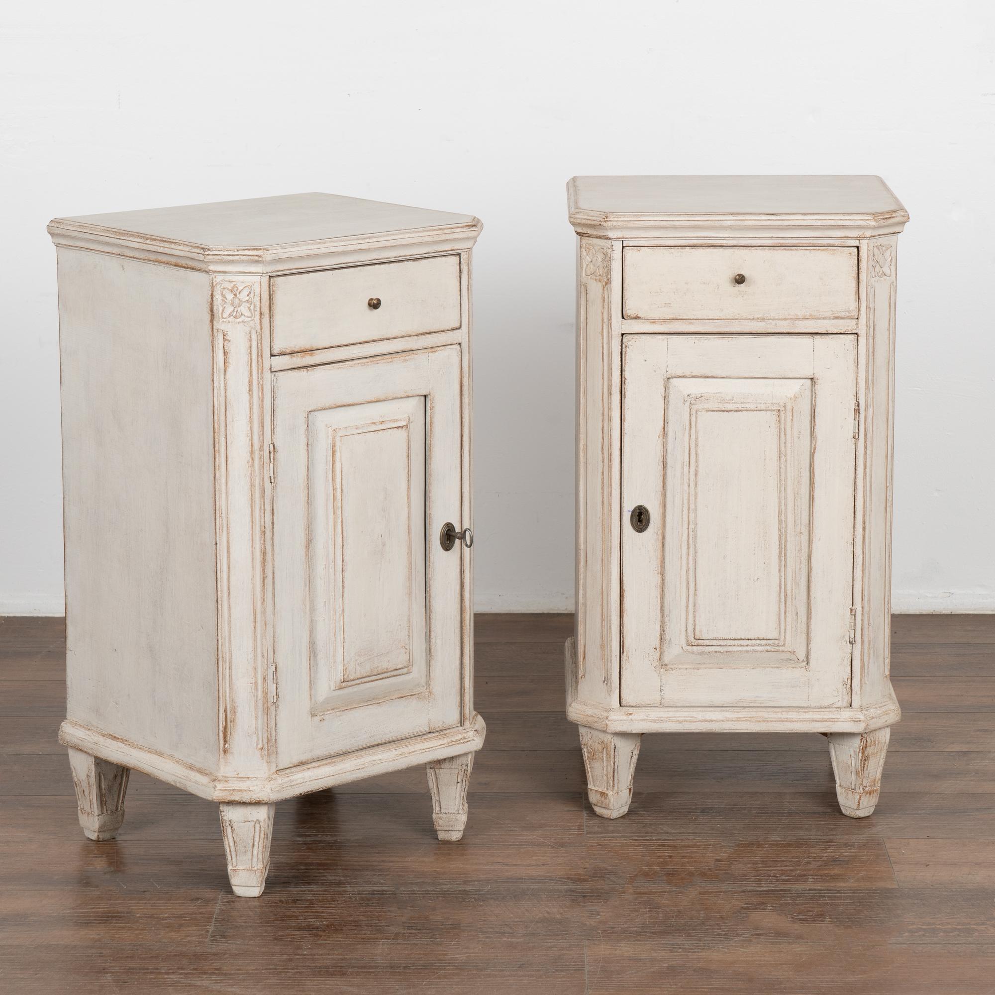 Pair, small Swedish country Gustavian style white painted nightstands or small cabinets standing on tapered feet.
Canted sides have simple fluted carving topped with floral medallion.
Newer professionally applied exterior white painted finish is