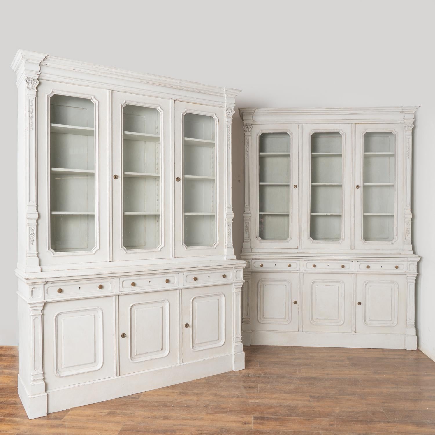 Pair of pine antique bookcases with adjustable interior shelving. The unique configuration of each cabinet incudes an upper single door with 20.75