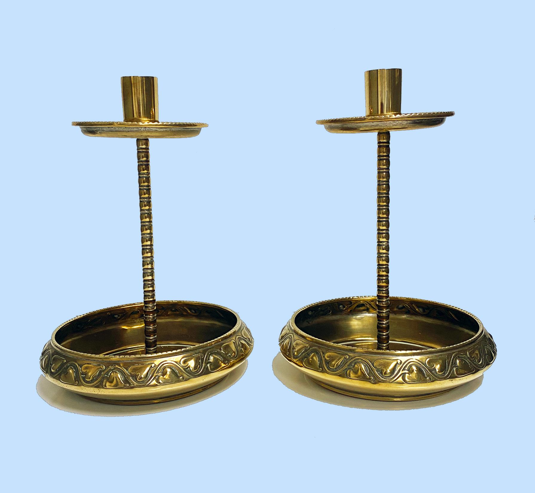 Pair of WMF brass Arts Crafts candlesticks C.1900. Unusual deep bases with heart swirl design decoration surround, bead borders and ovolo tubular central stems. Original rich brass patina. Have not been polished up. All pieces unscrew for easy